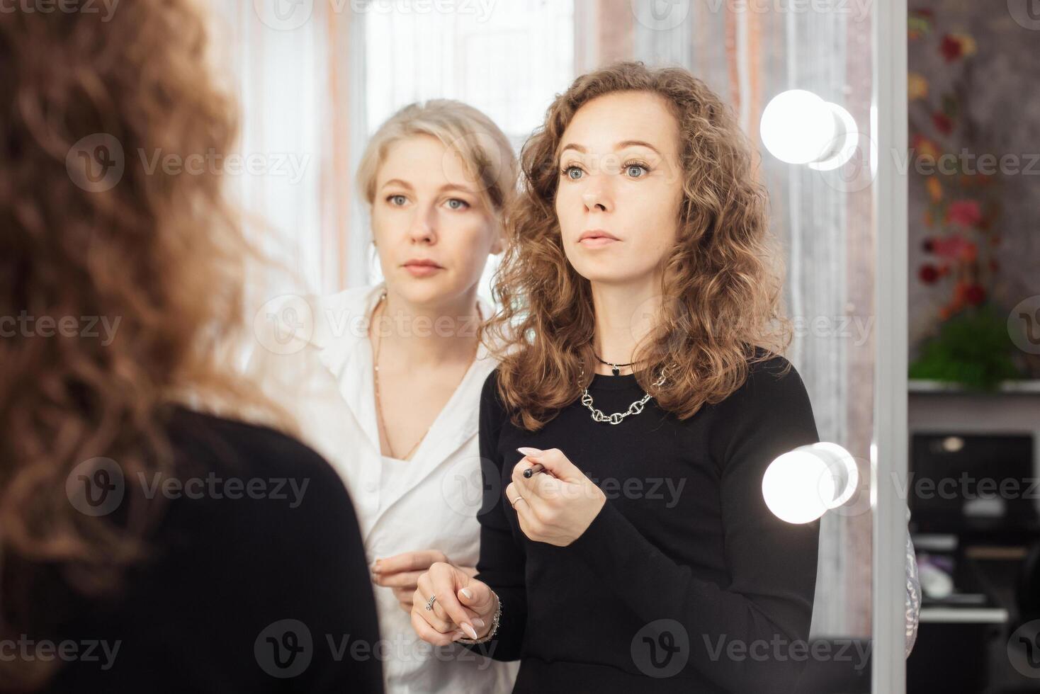 A professional makeup artist conducts a master class on professional development, observing the student's work. photo