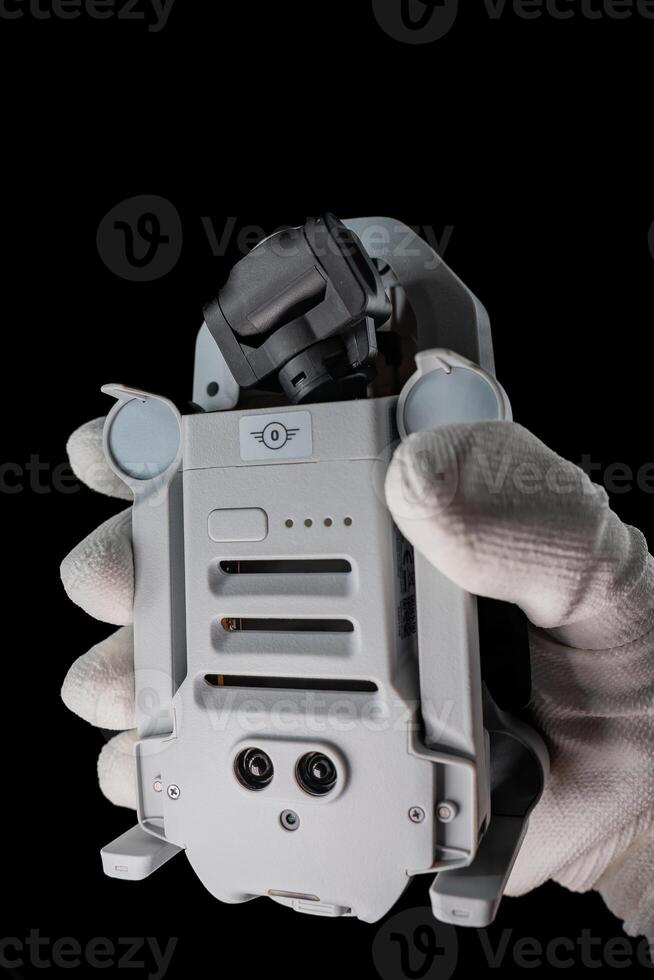 Technician Holding Compact Drone Against Black Background, Daytime photo