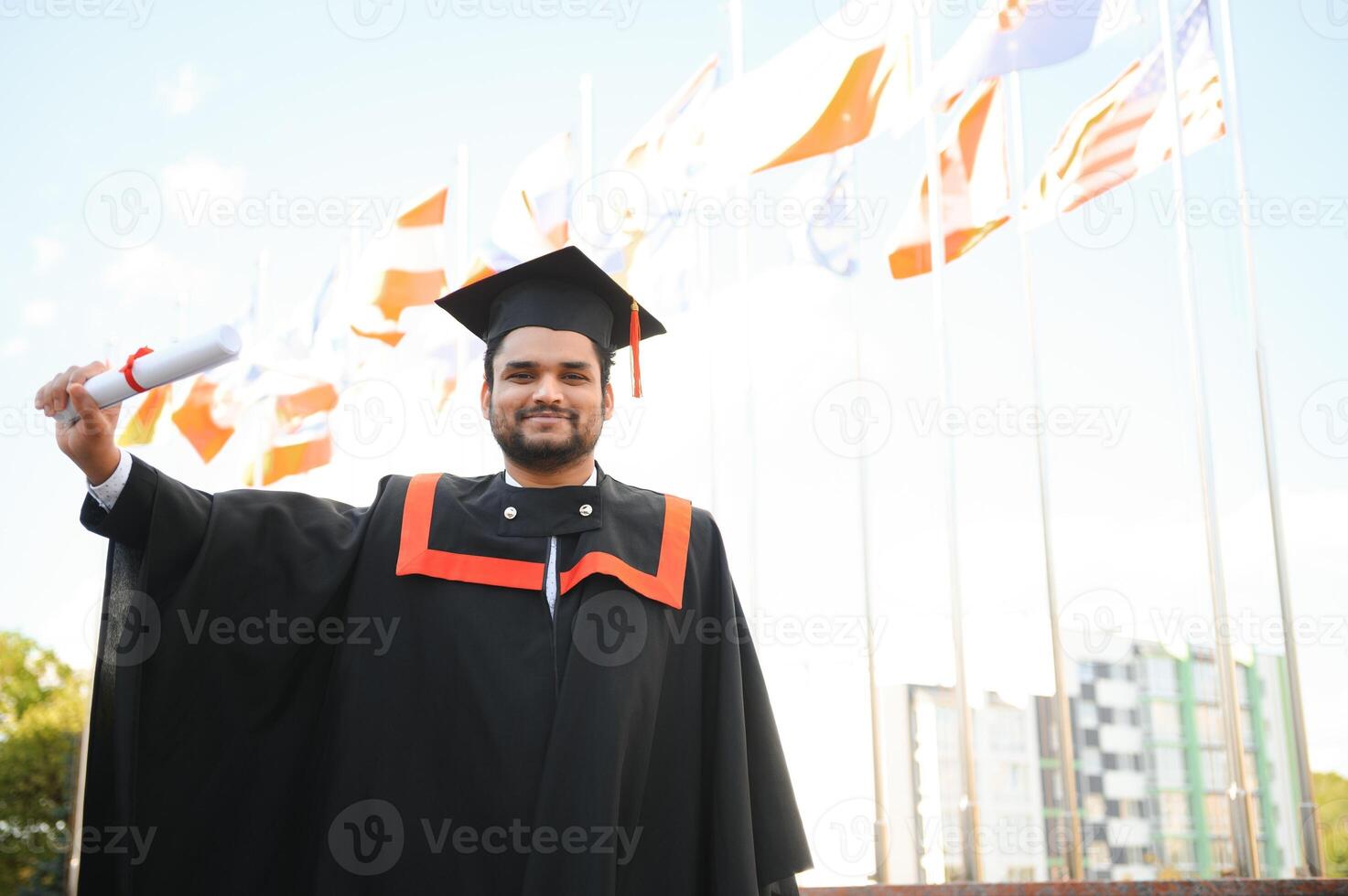 Handsome indian graduate in graduation glow with diploma photo