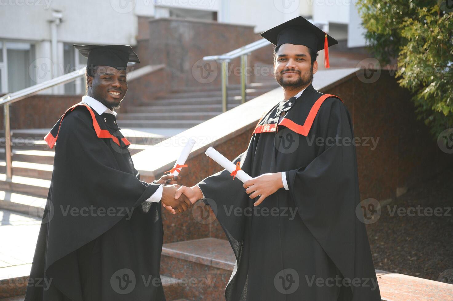 Group of multiracial graduate students with diplomas on university background photo