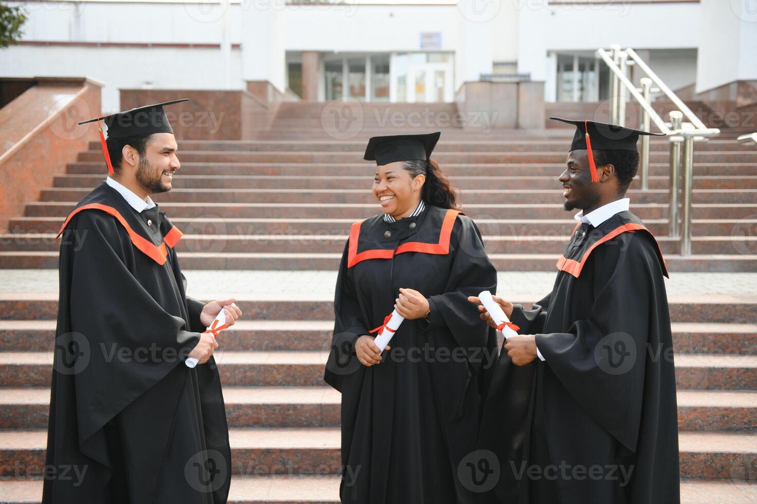 education, graduation and people concept - group of happy international students in mortar boards and bachelor gowns with diplomas photo