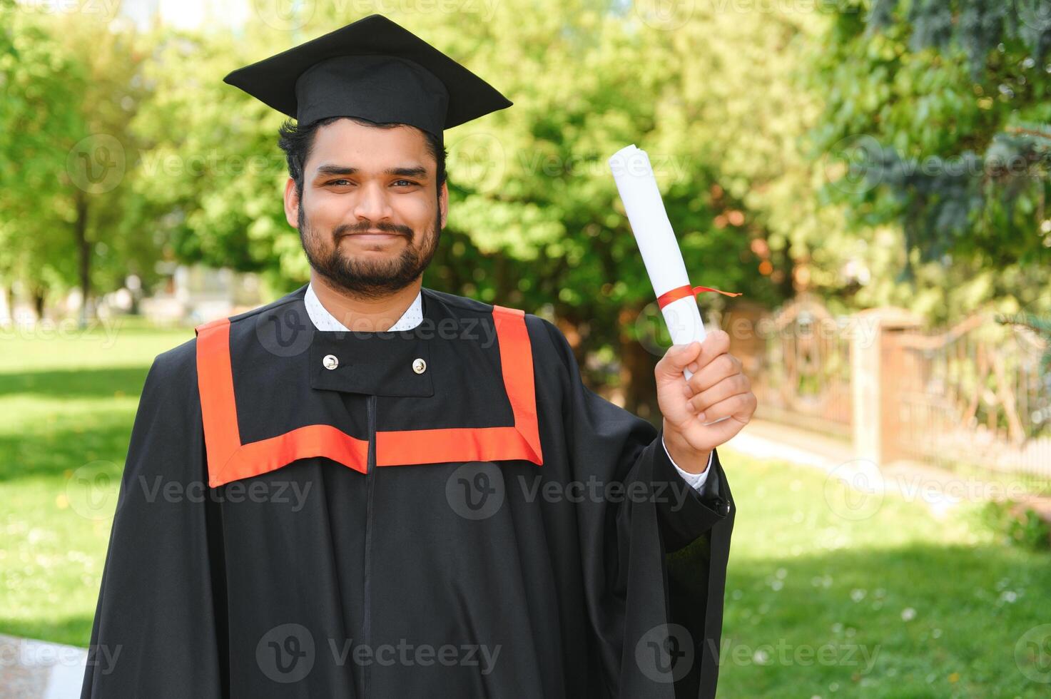 Handsome indian graduate in graduation glow with diploma photo