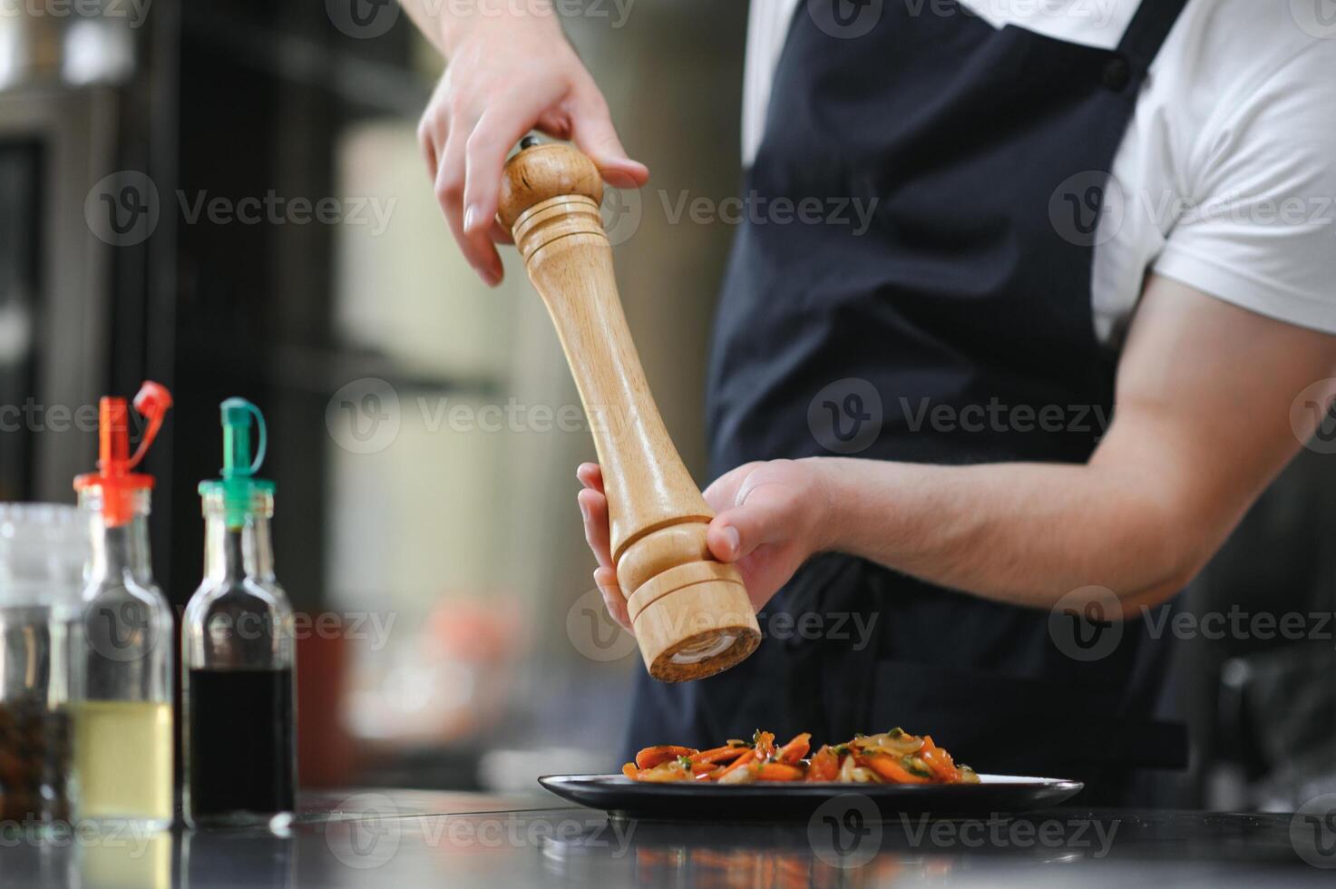Closeup of a concentrated male chef garnishing food in the kitchen photo