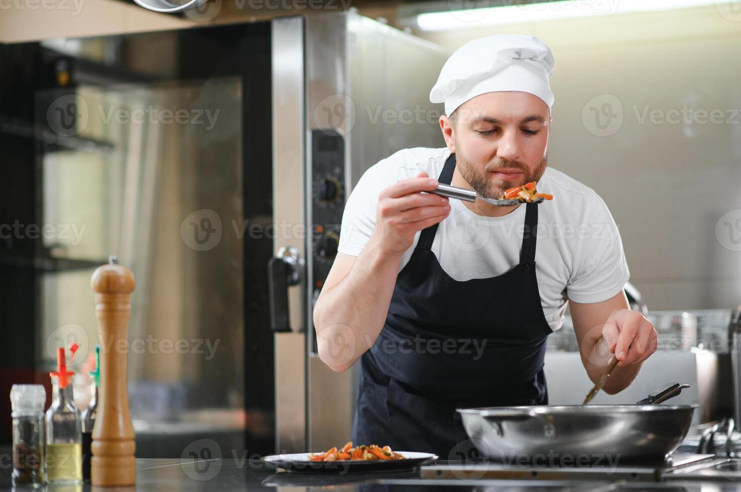 Portrait of handsome positive chef cook at the restaurant kitchen photo