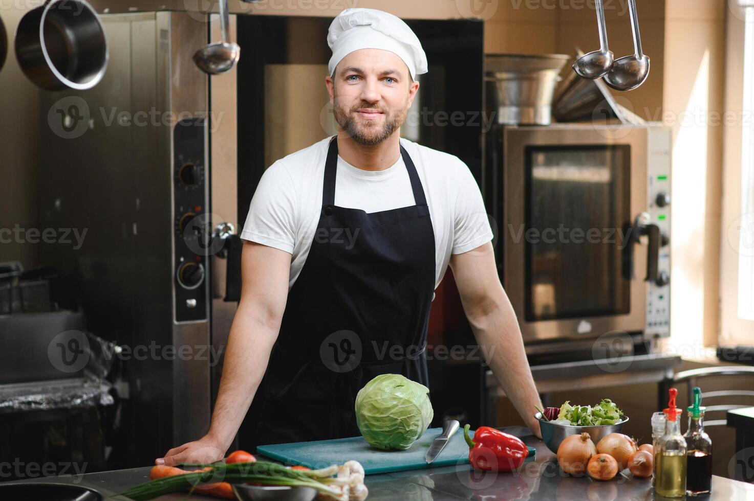 Portrait of handsome positive chef cook at the restaurant kitchen photo