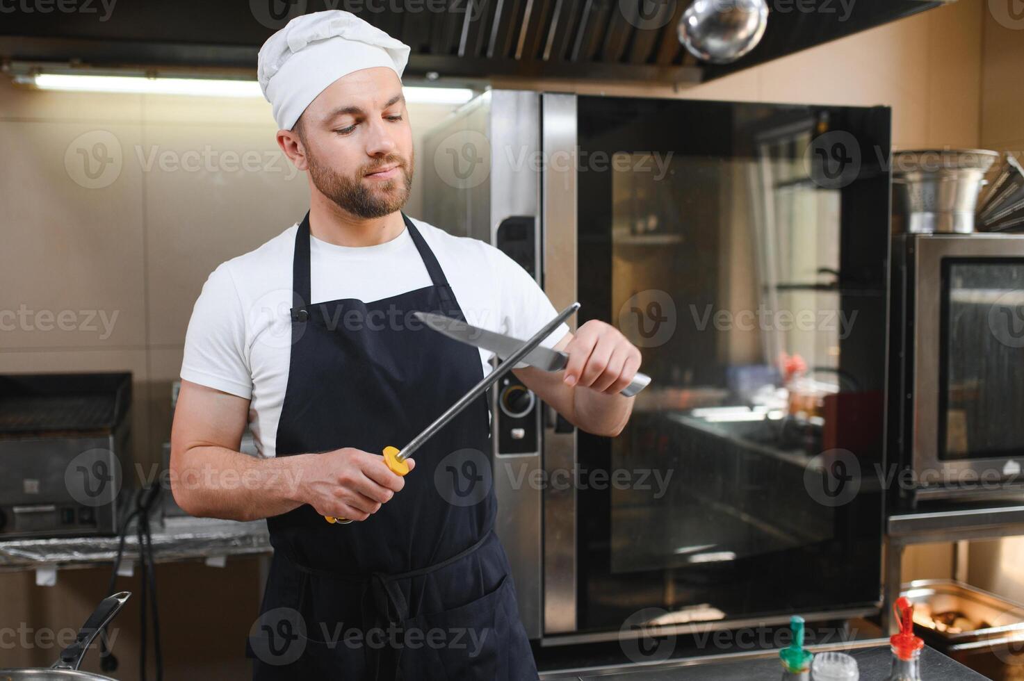 Chef sharpening knife for cutting meat in commercial kitchen photo