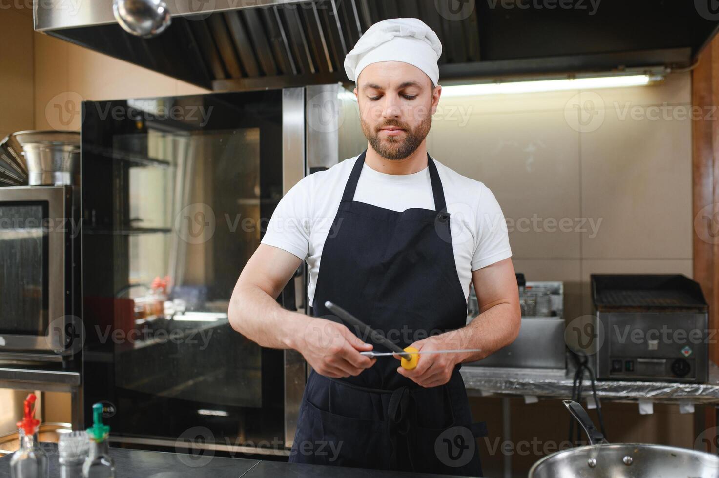 Chef sharpening knife for cutting meat in commercial kitchen photo