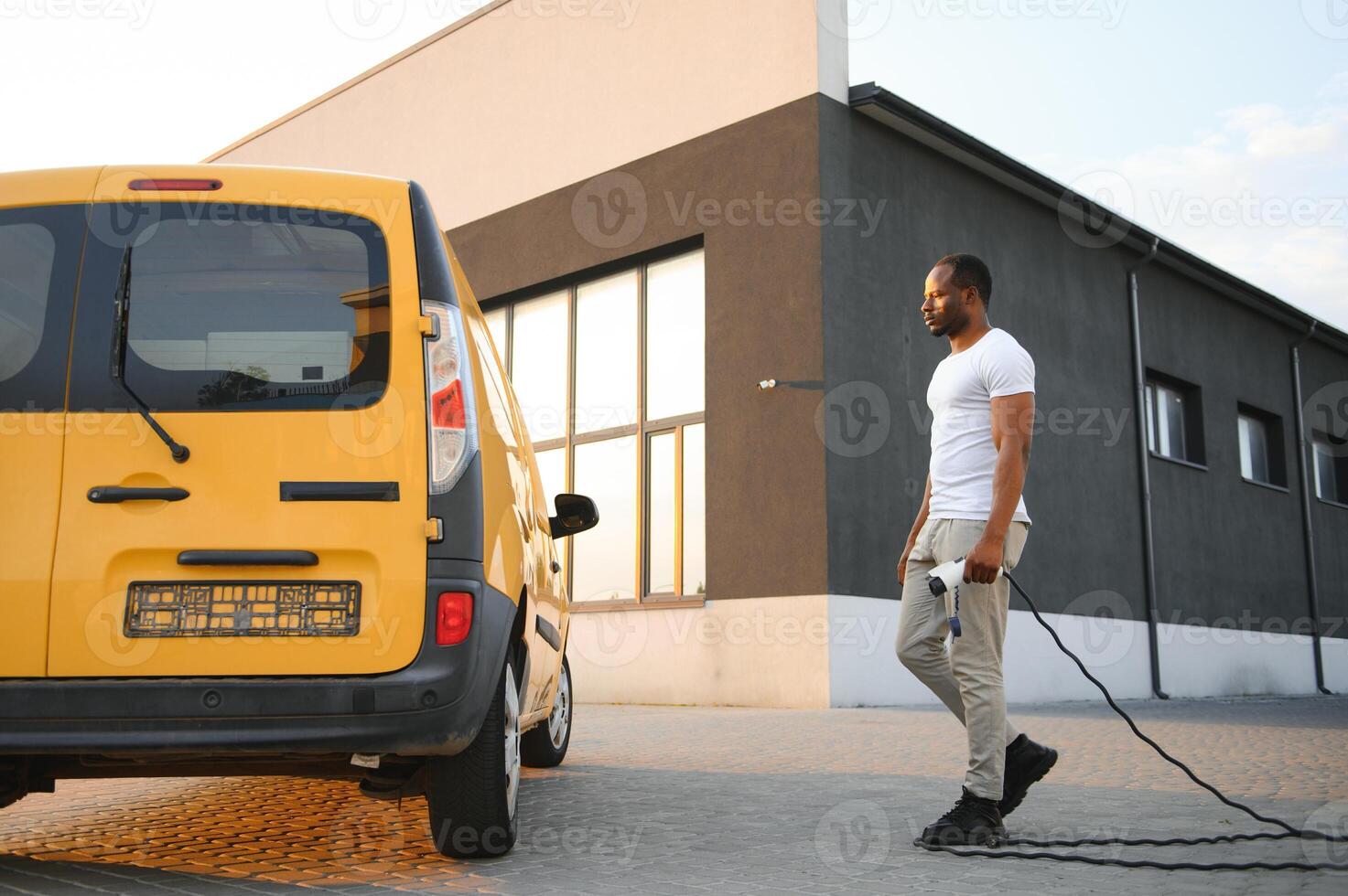 African American man charging his electric car. photo