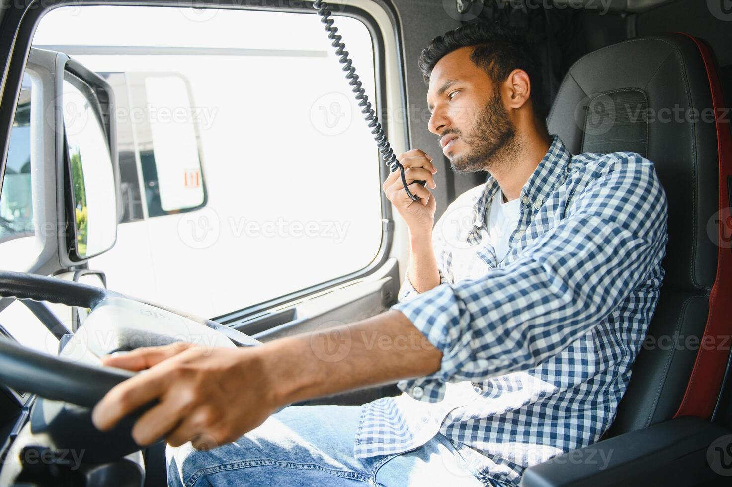 Using radio. Young truck driver is with his vehicle at daytime. photo