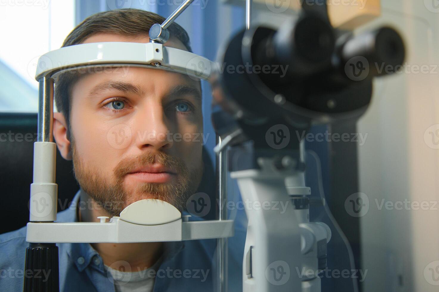 Handsome young man is checking the eye vision in modern ophthalmology clinic. Patient in ophthalmology clinic photo