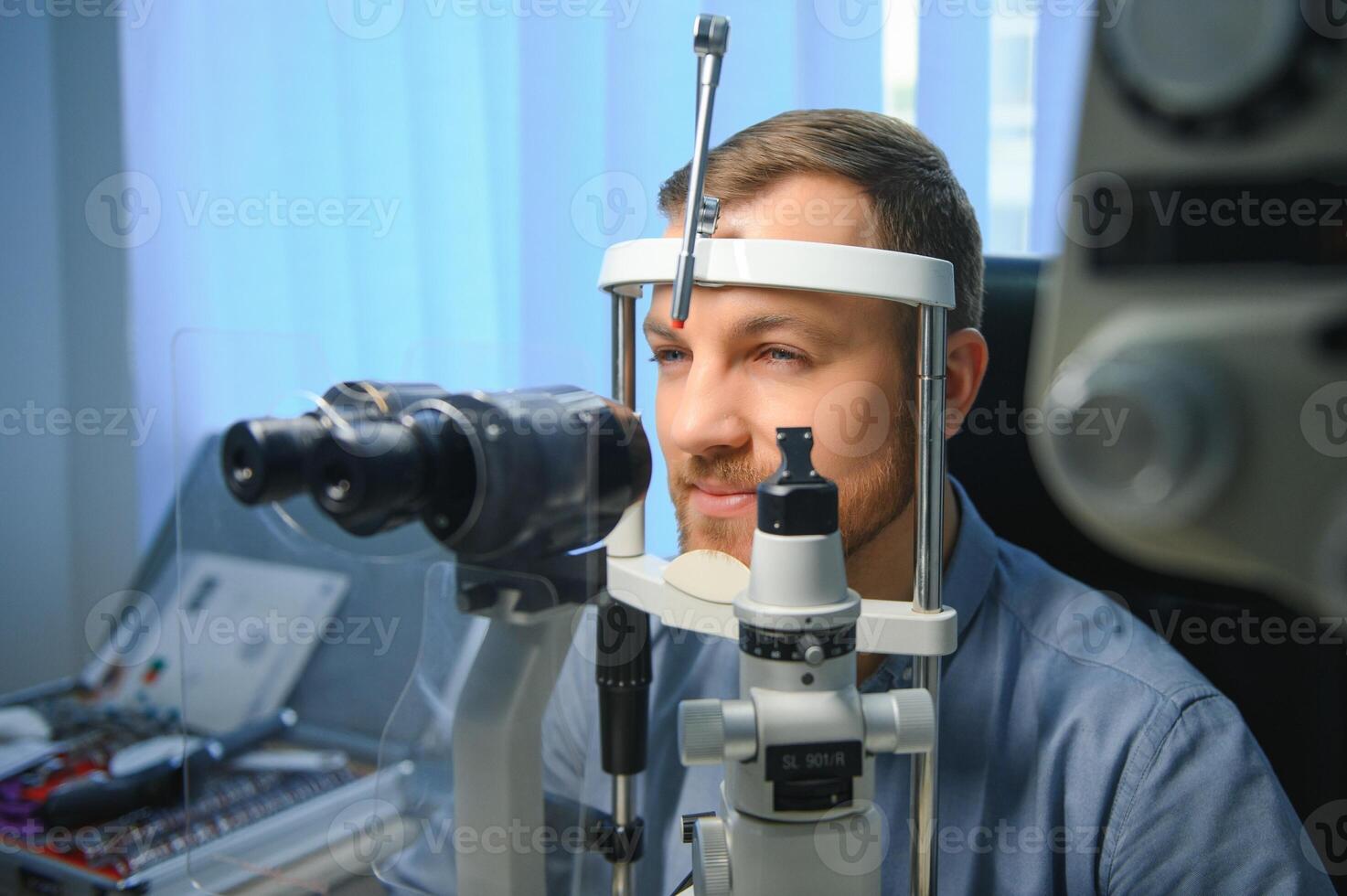 Handsome young man is checking the eye vision in modern ophthalmology clinic. Patient in ophthalmology clinic photo