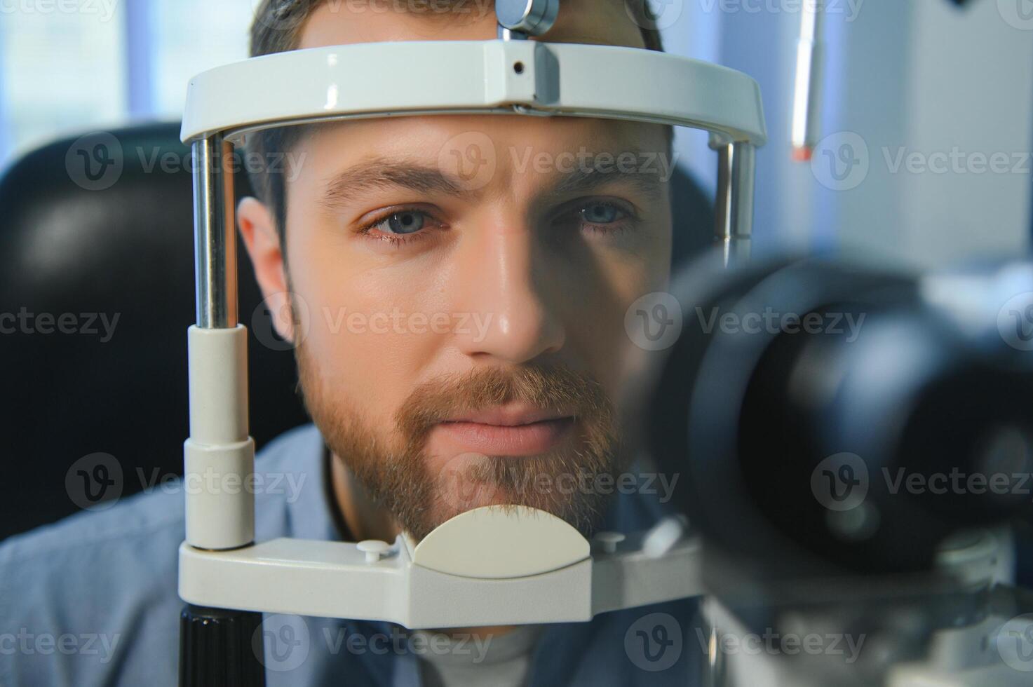 Handsome young man is checking the eye vision in modern ophthalmology clinic. Patient in ophthalmology clinic photo
