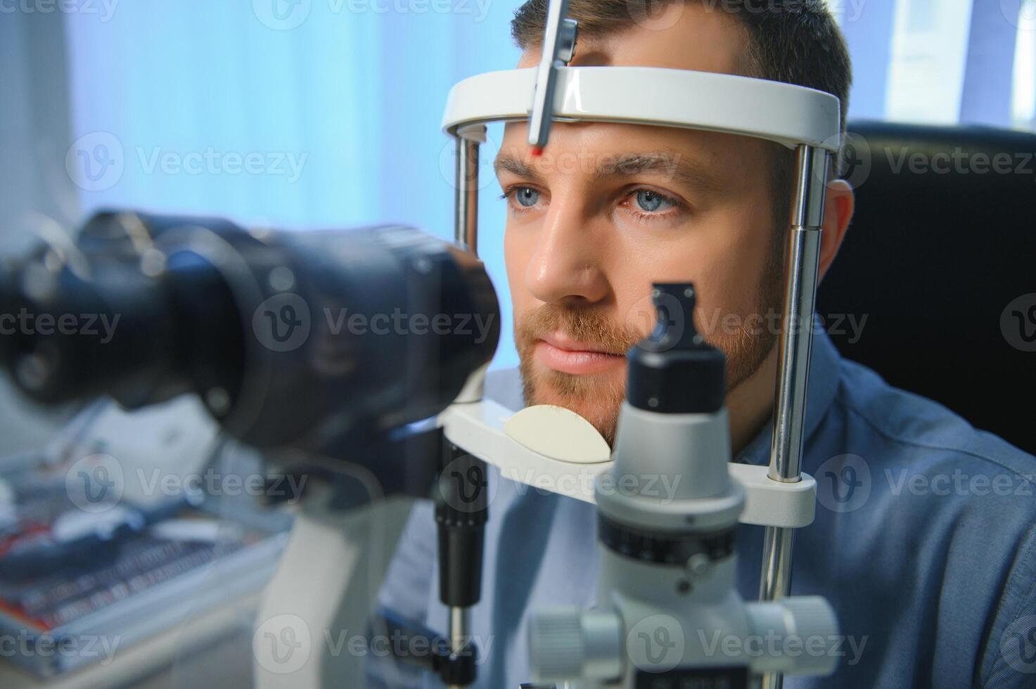 Handsome young man is checking the eye vision in modern ophthalmology clinic. Patient in ophthalmology clinic photo