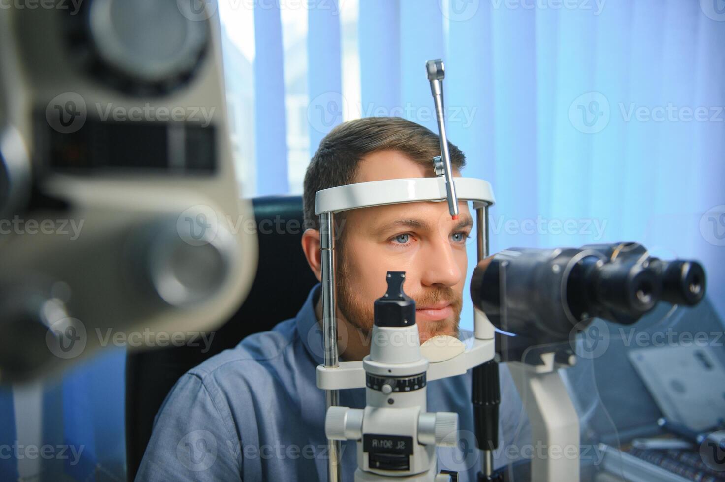 Handsome young man is checking the eye vision in modern ophthalmology clinic. Patient in ophthalmology clinic photo