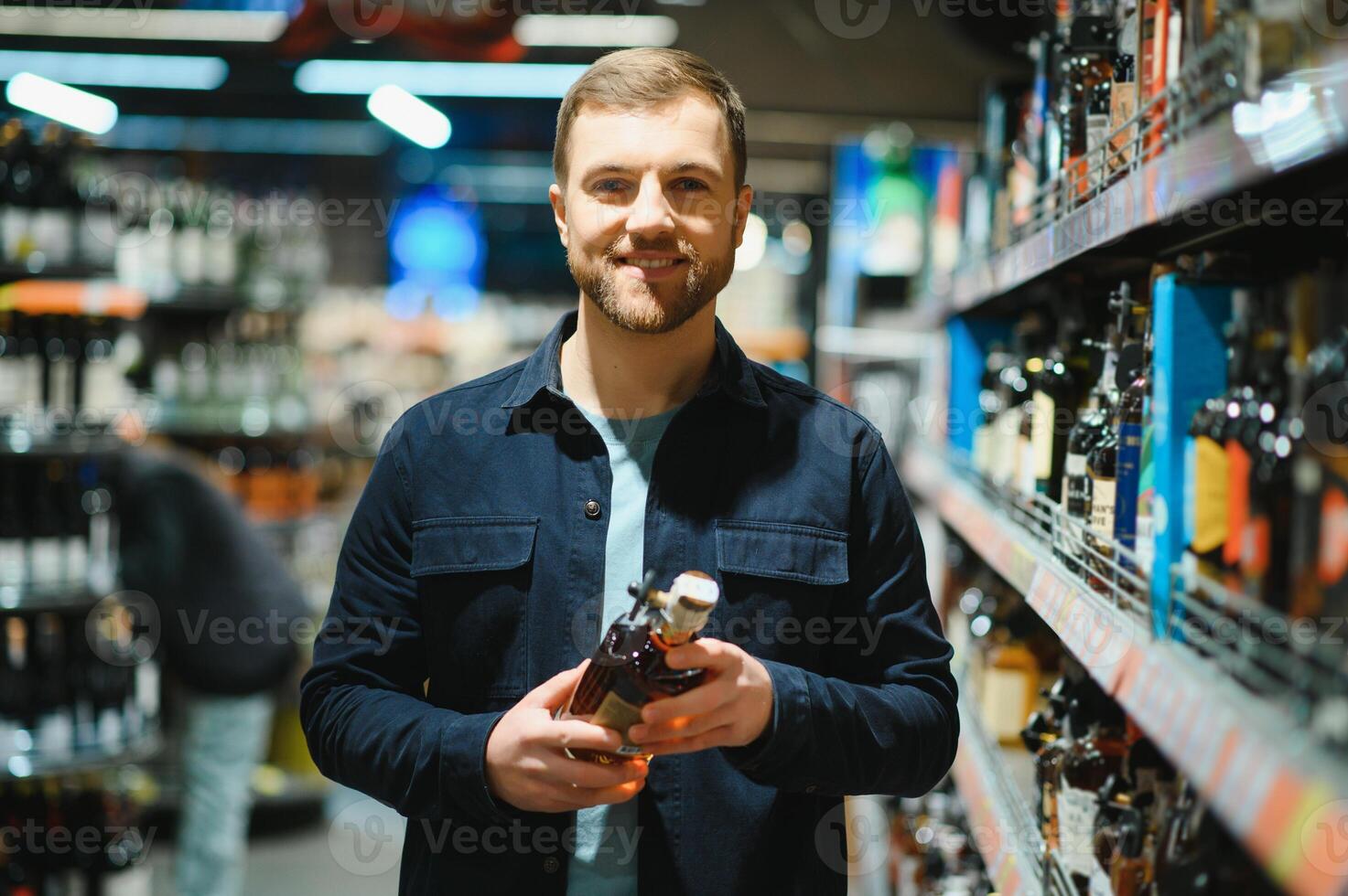 A man takes alcoholic drinks from the supermarket shelf. Shopping for alcohol in the store. photo