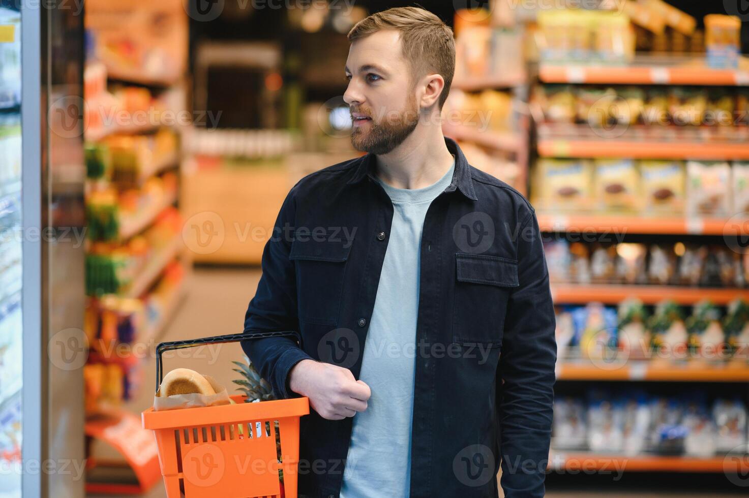 Portrait of smiling man walking with his trolley on aisle at supermarket. photo