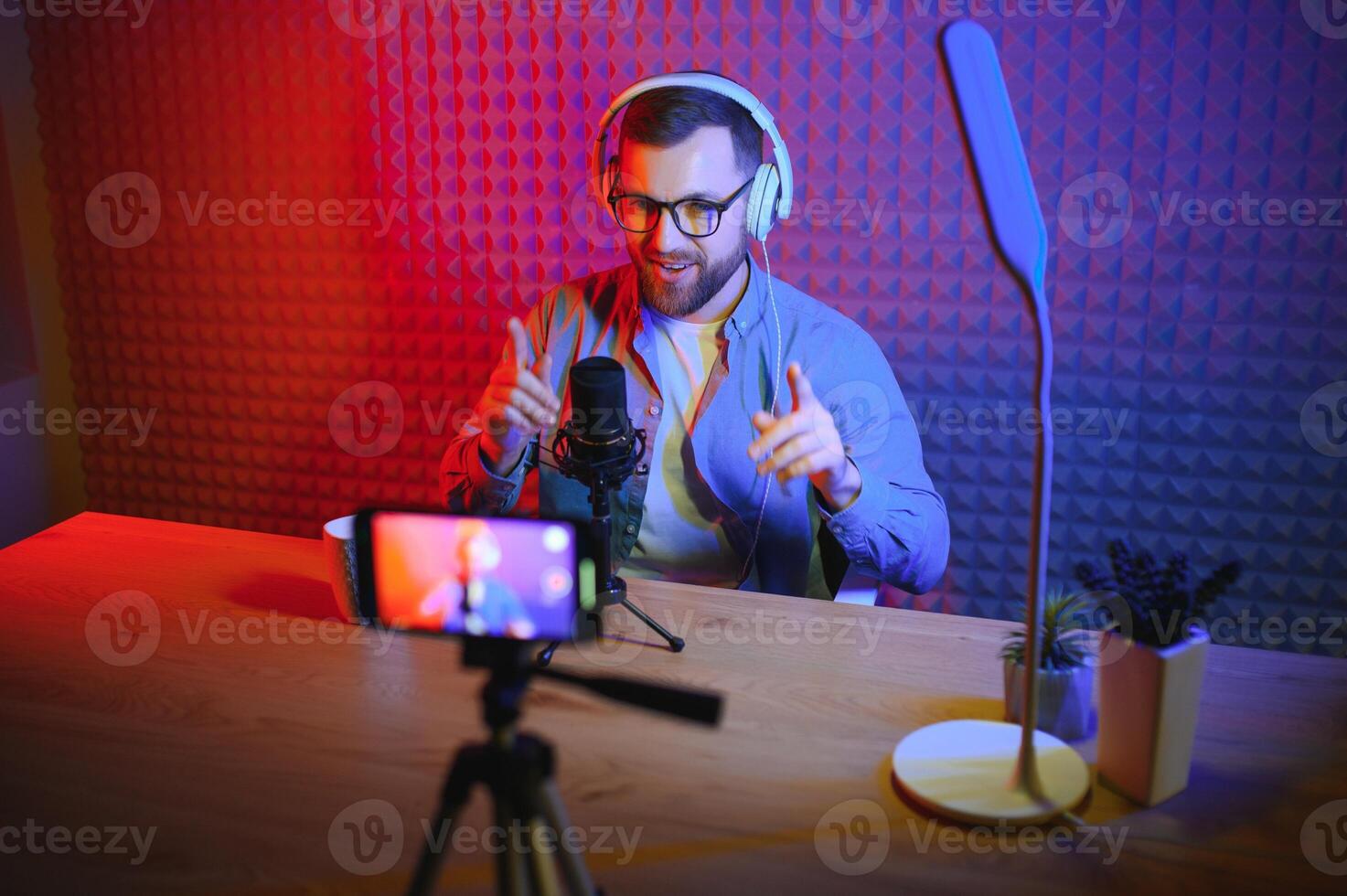 Young man recording or streaming podcast using microphone at his small broadcast studio. Content creator. photo
