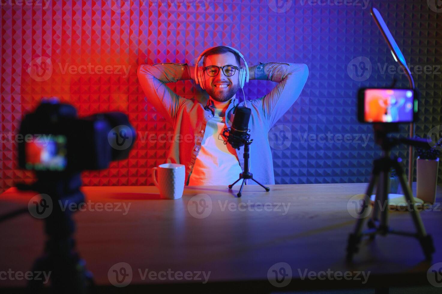 Young man recording or streaming podcast using microphone at his small broadcast studio. Content creator. photo