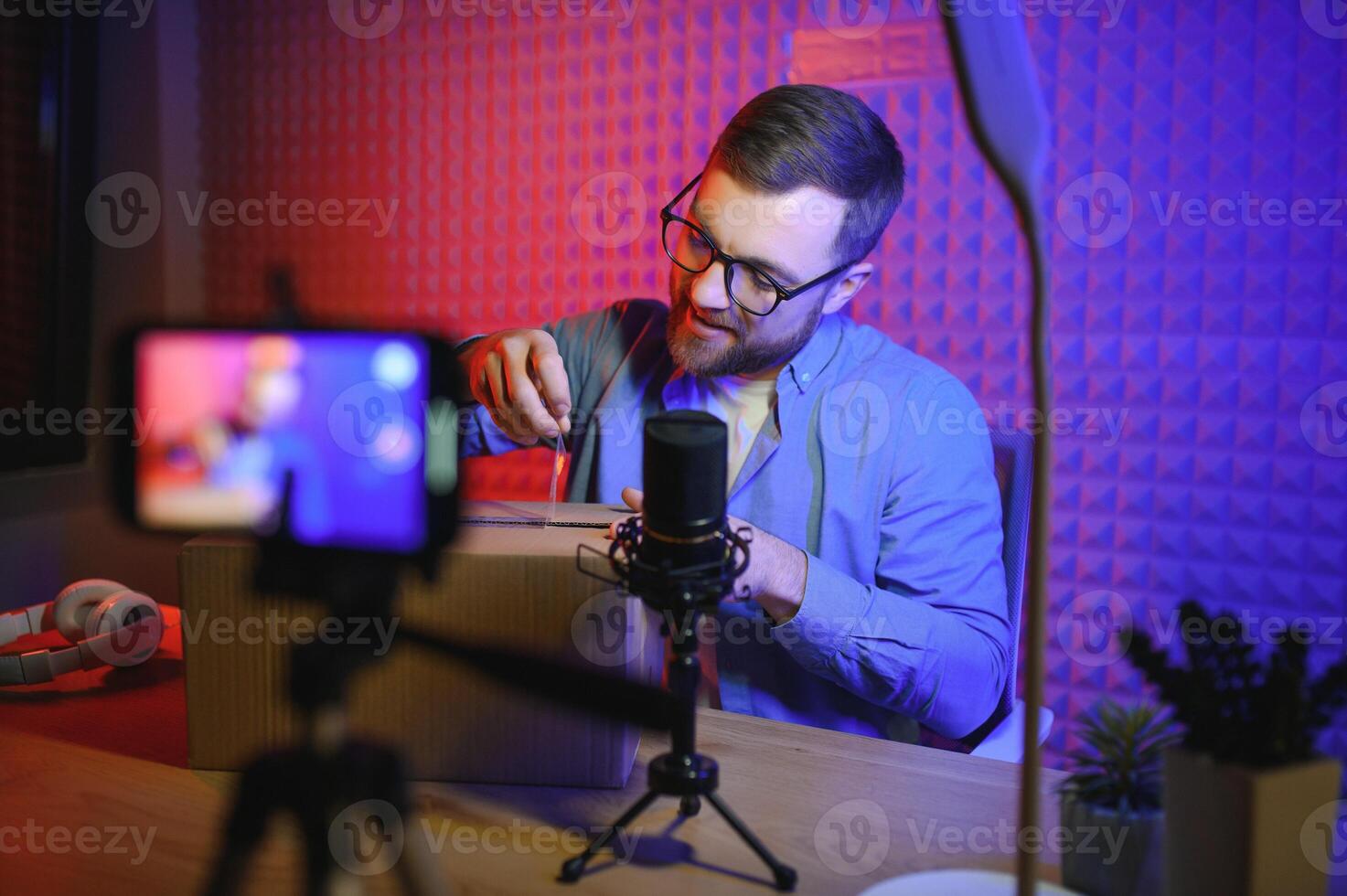 young adult man creating online content for the channel, daily vlog, unboxing a brand new phone at home, online sales photo