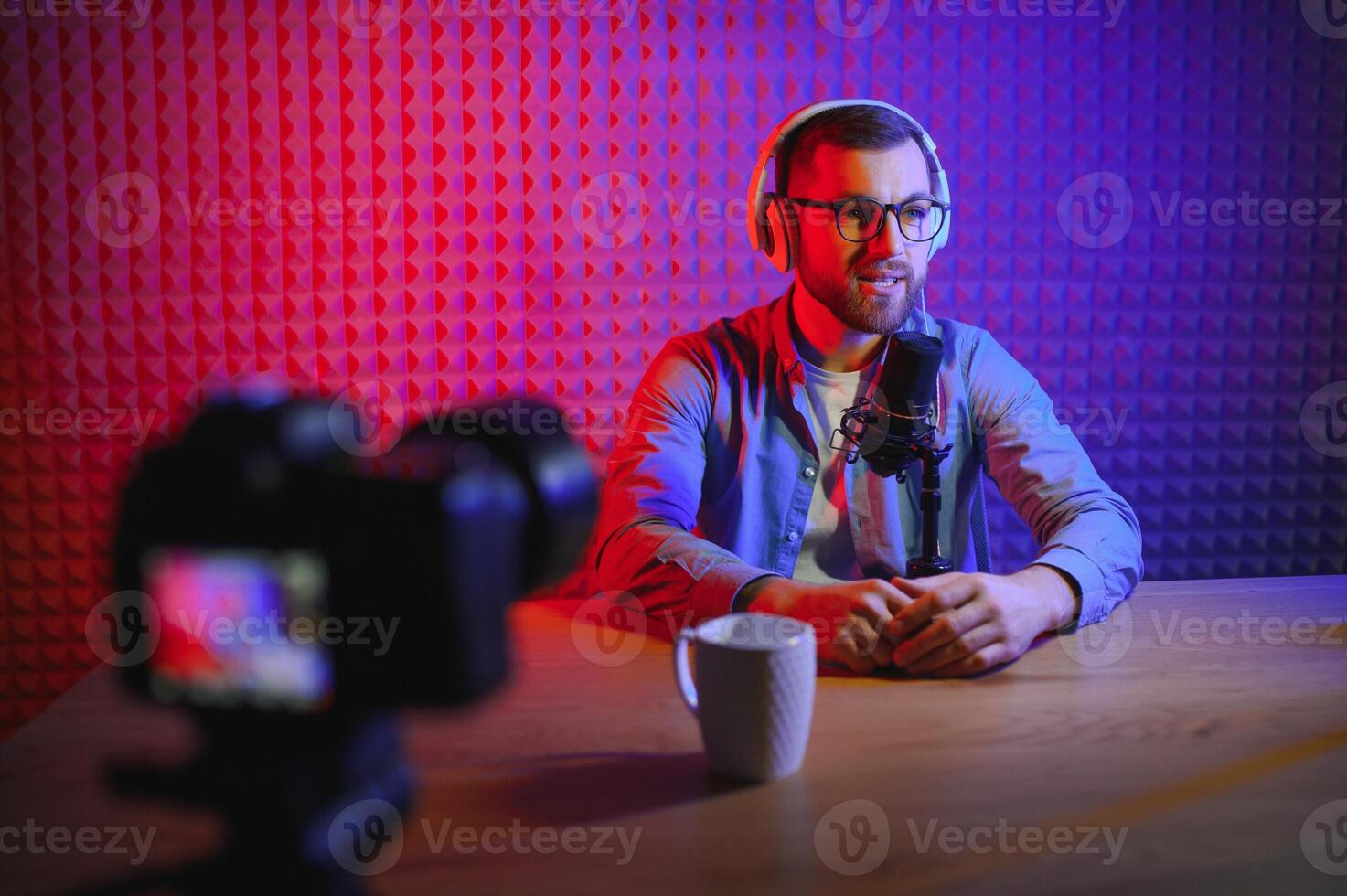 Young man recording or streaming podcast using microphone at his small broadcast studio. Content creator. photo