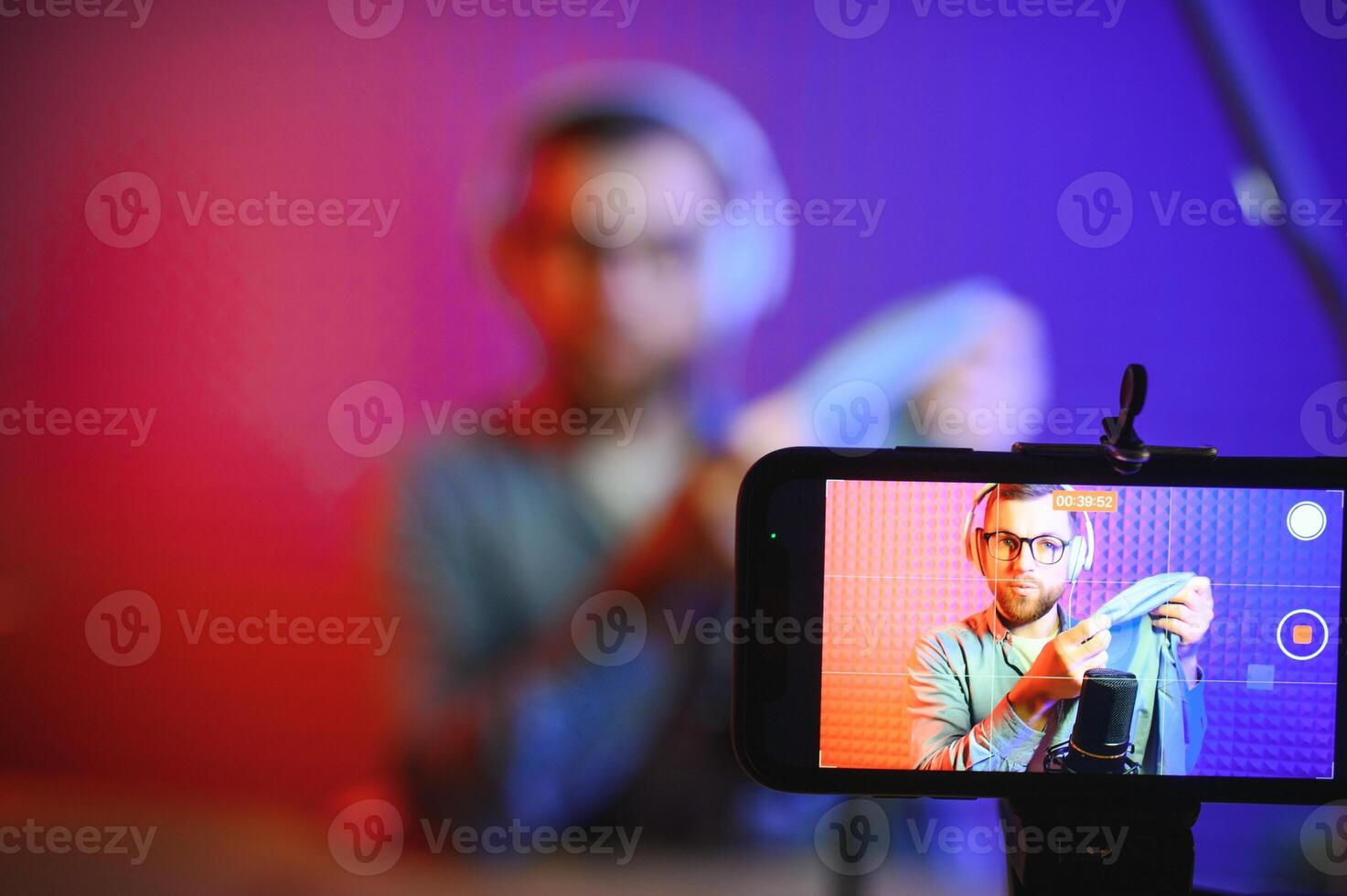 Panoramic view of young adult vlogger creating internet content, holding carton box in hands, unpacking received pack and recording media online on broadcast equipment photo