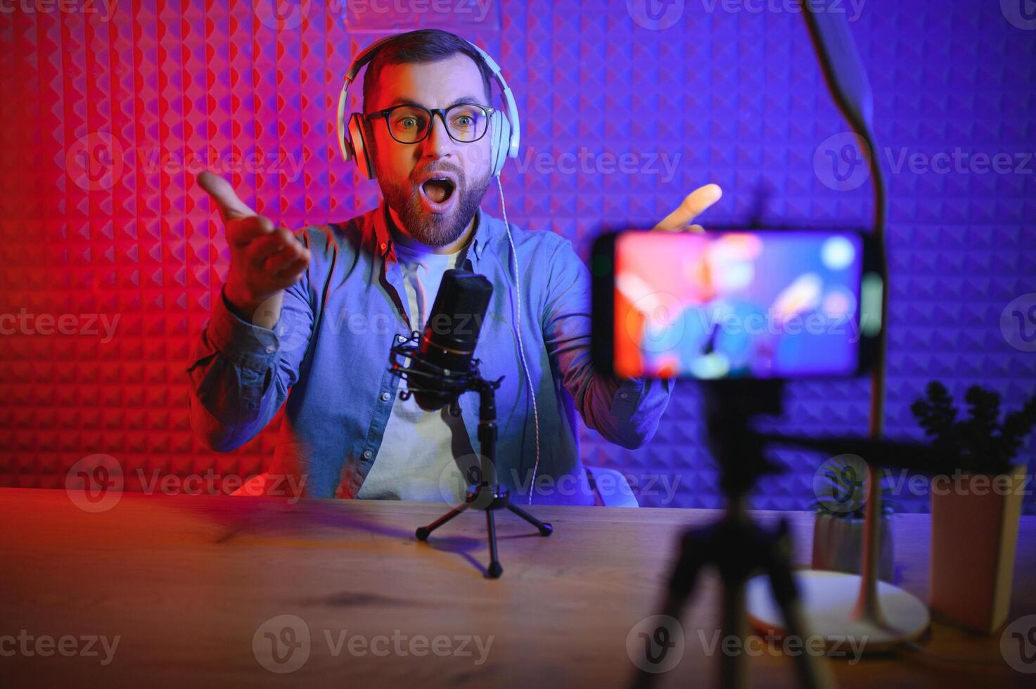 Young man recording or streaming podcast using microphone at his small broadcast studio. Content creator. photo