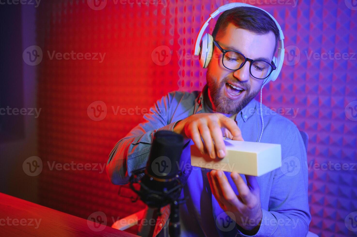 Young man recording or streaming podcast using microphone at his small broadcast studio. Content creator. photo
