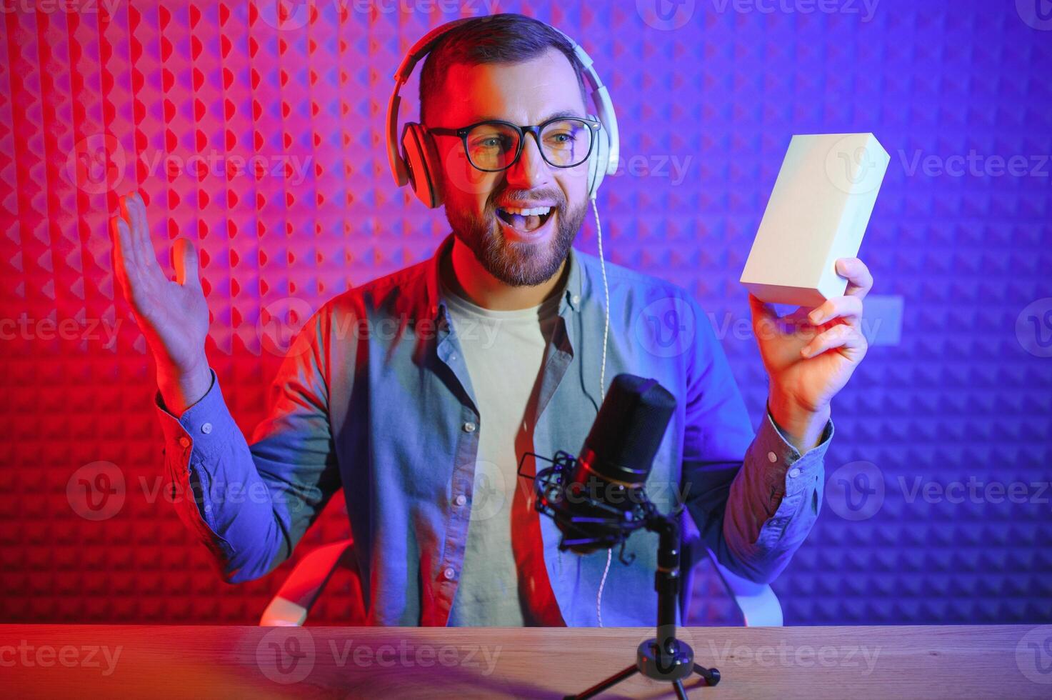 Young man recording or streaming podcast using microphone at his small broadcast studio. Content creator. photo