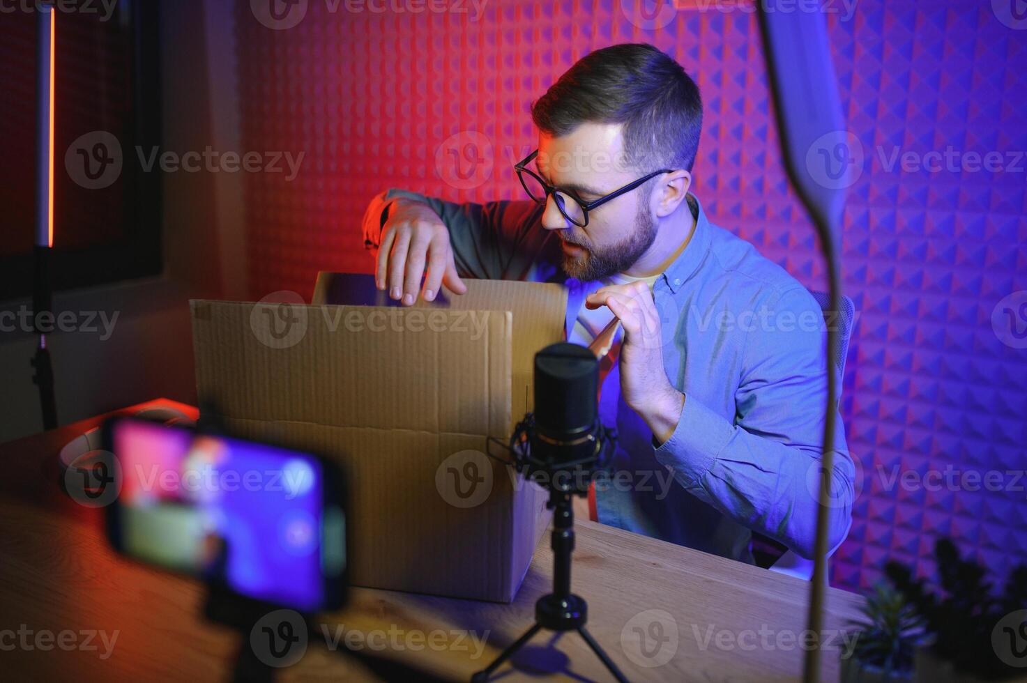 Joyful young man recording unboxing in studio photo