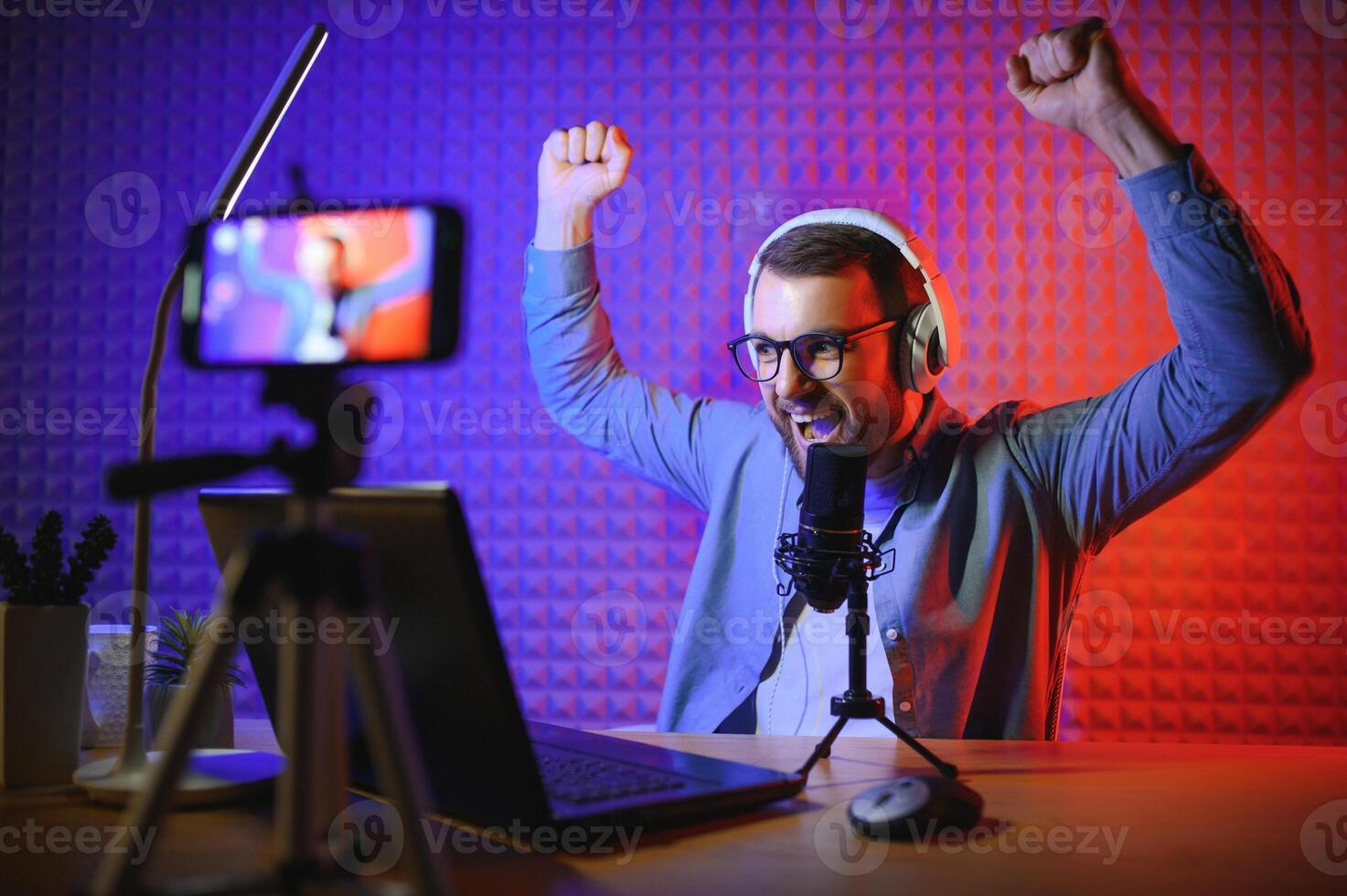 Young man recording or streaming podcast using microphone at his small broadcast studio. Content creator. photo