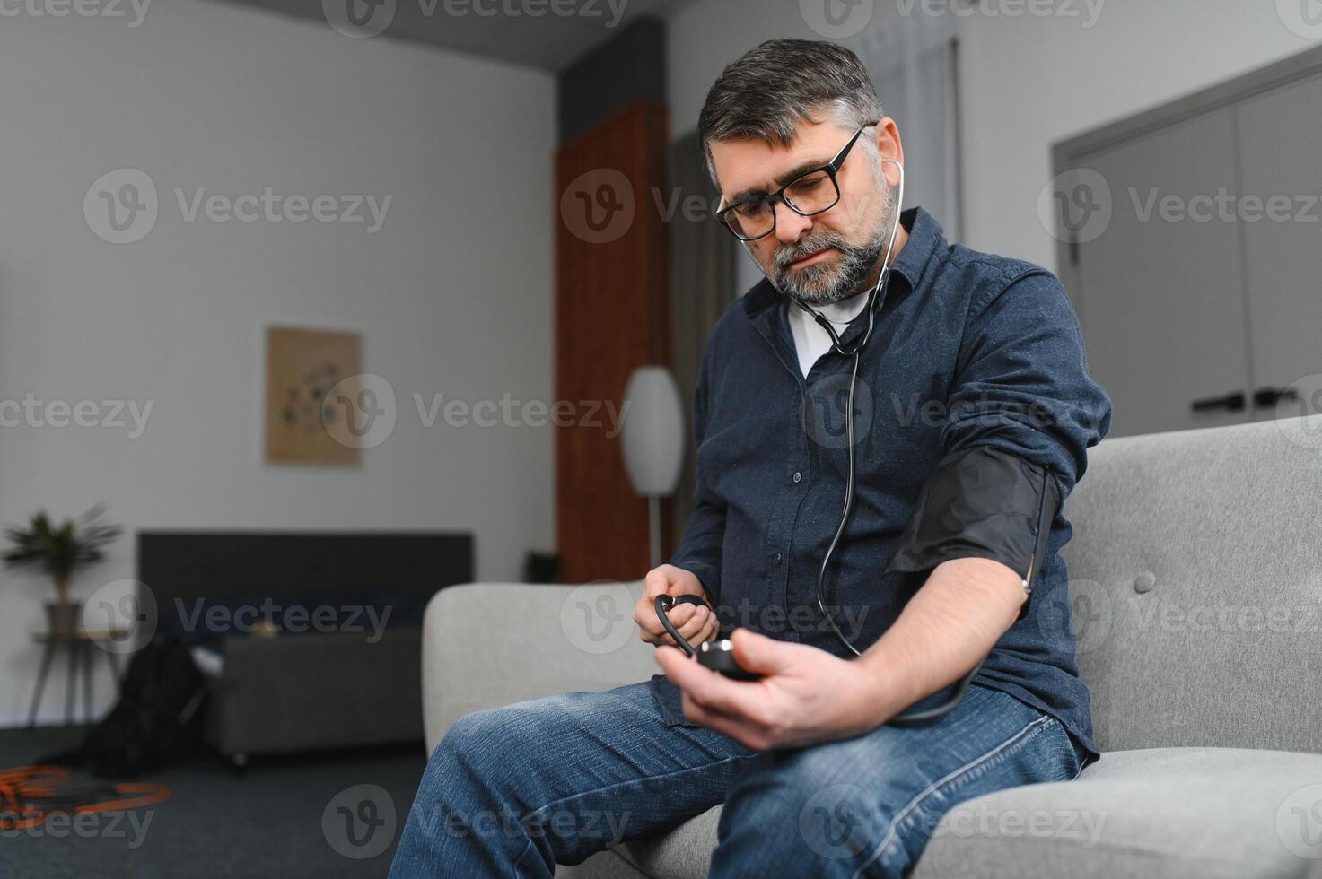 Senior caucasian retired male taking blood pressure at home photo