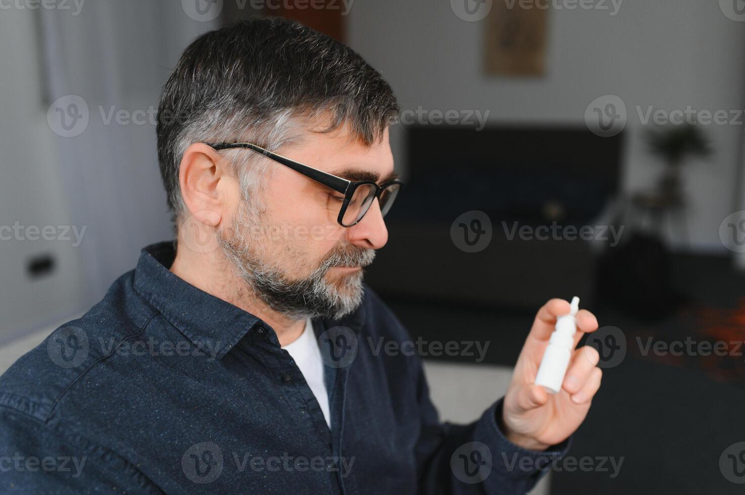 Sick man with nasal spray at home. photo