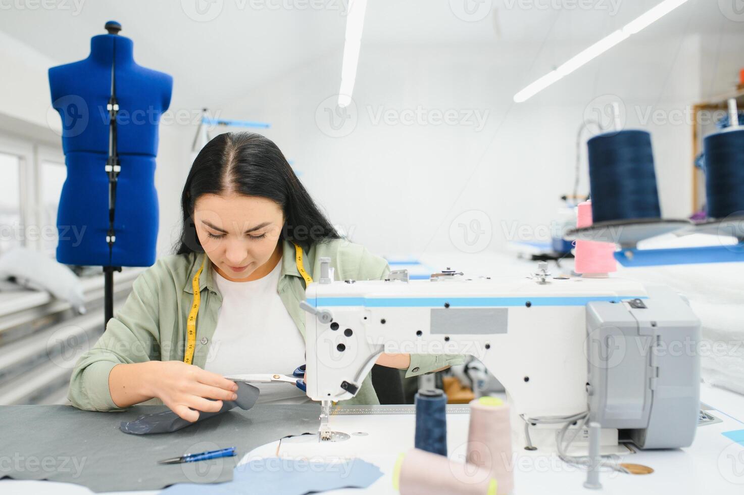 Young woman working as seamstress in clothing factory. photo