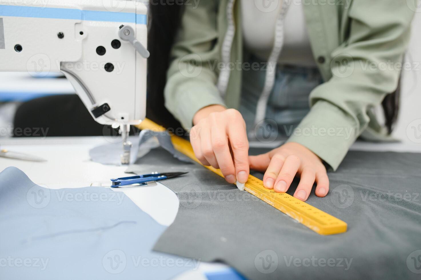 Happy female dressmaker working with sewing machine at textile factory. photo