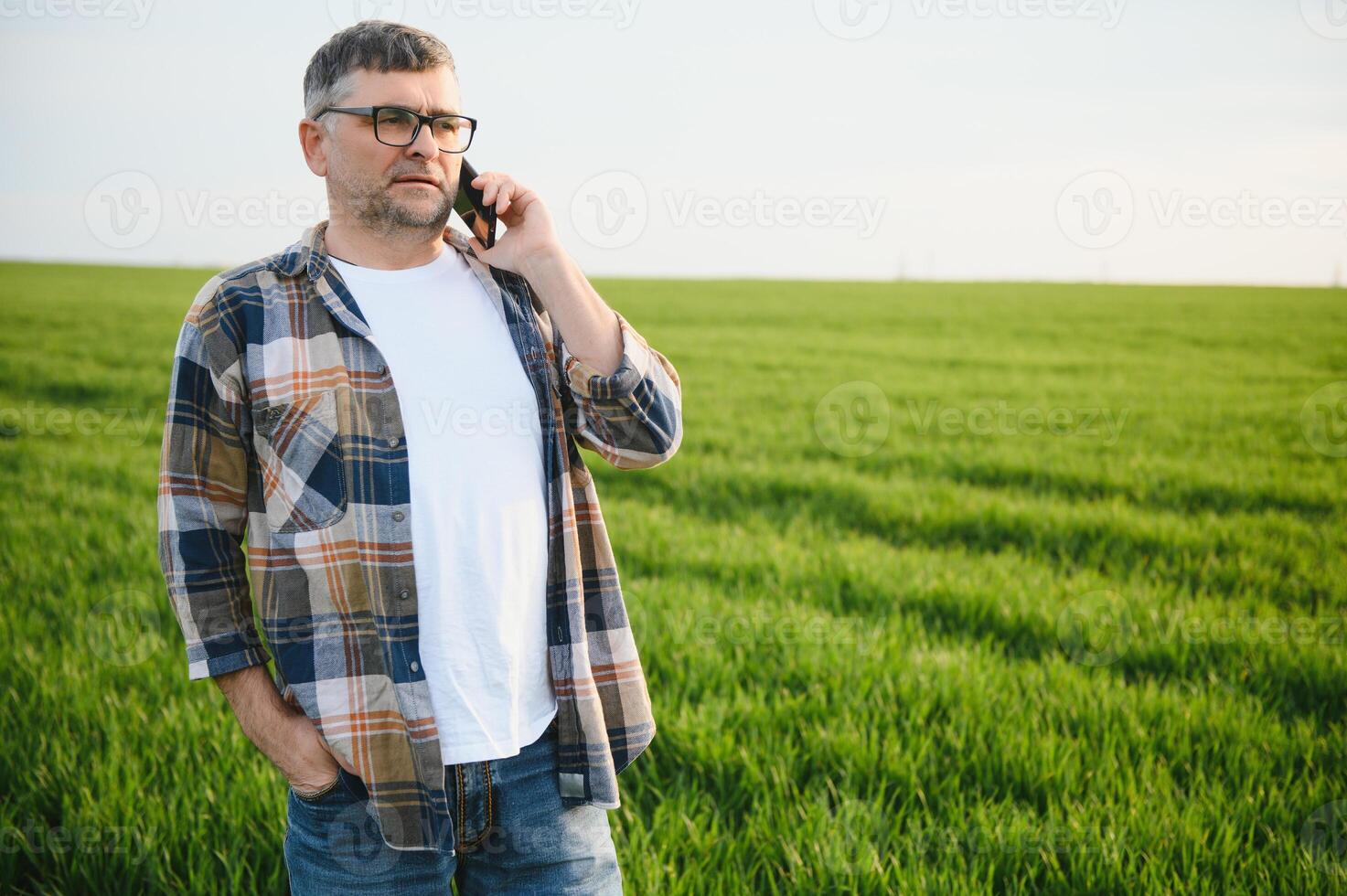 Portrait of senior farmer standing in wheat field examining crop during the day. photo