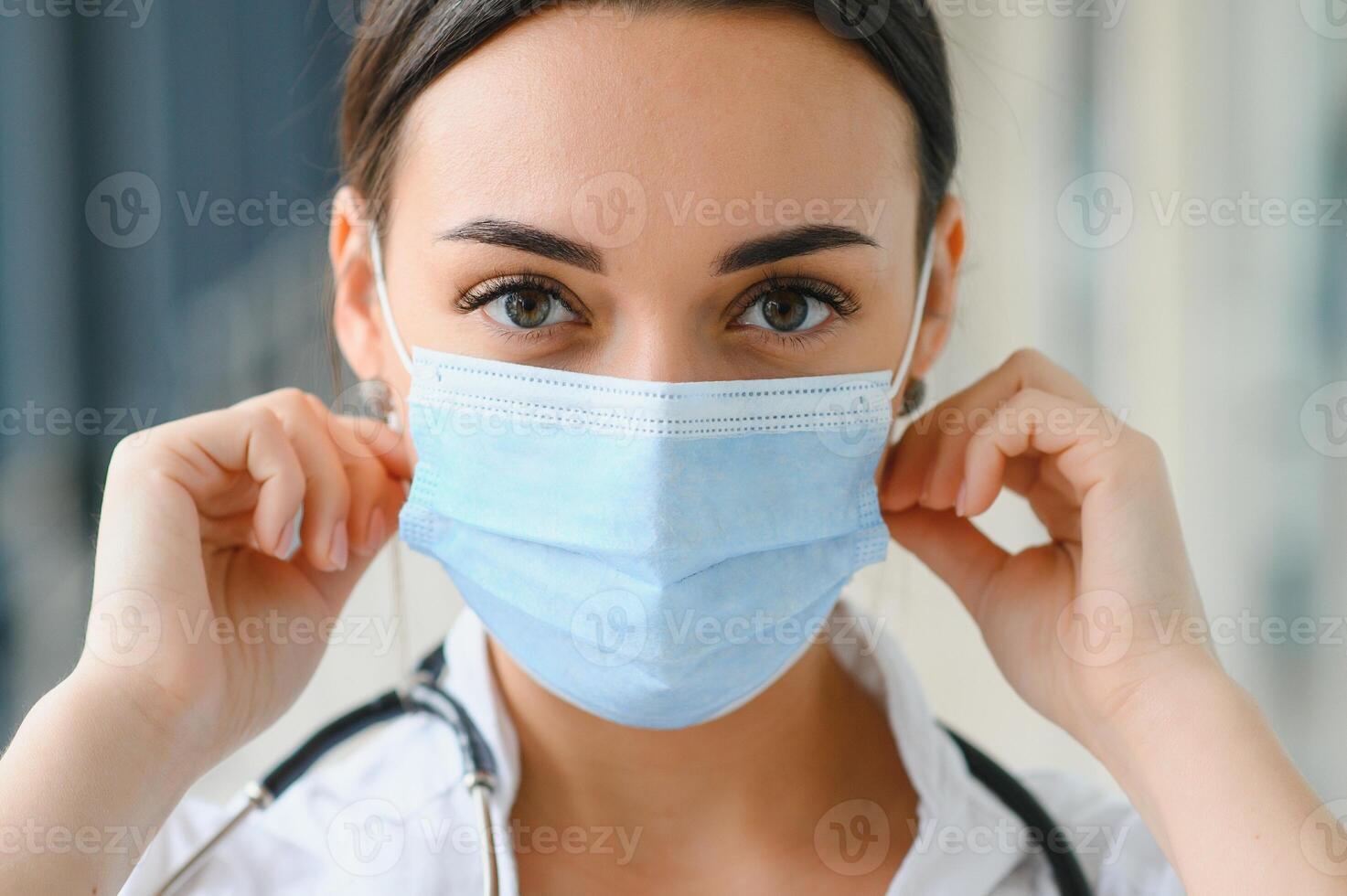 Portrait of young beautiful female medical worker,wearing uniform and protective face mask photo