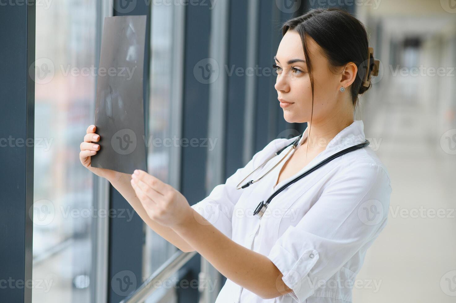 Young female doctor looking at the x-ray picture of lungs in hospital. photo