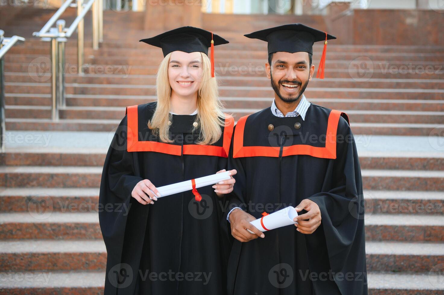 a multiracial group of graduates. Indian male graduate and European female student happy with diplomas in hands. photo