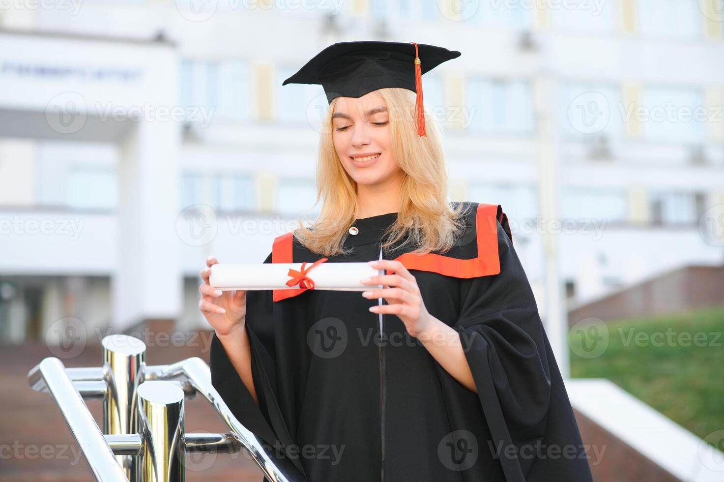 Portrait enthusiastic female college student graduate in cap and gown celebrating, holding diploma. photo