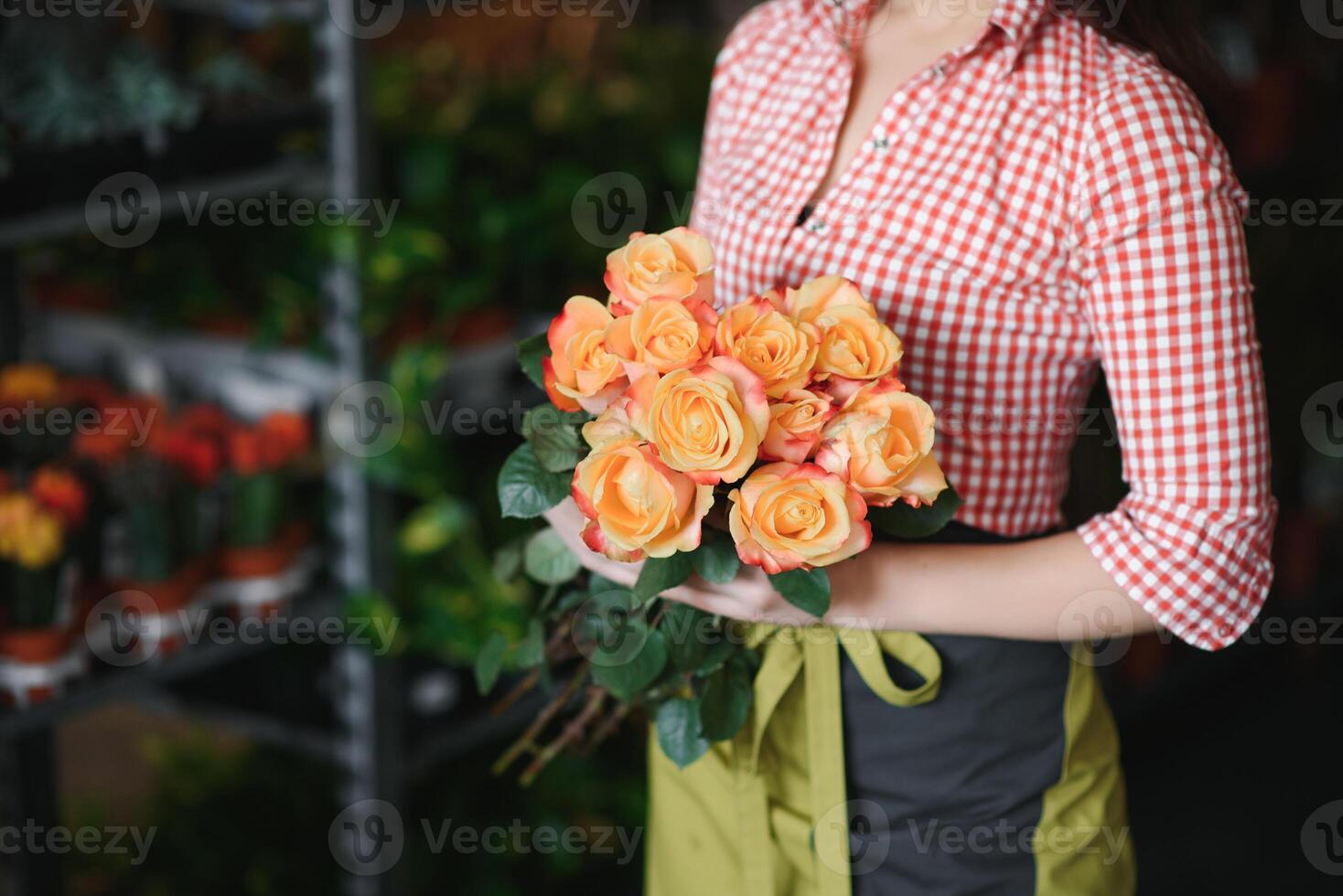 Young beautiful woman florist make bouquet of flowers at flower shop photo