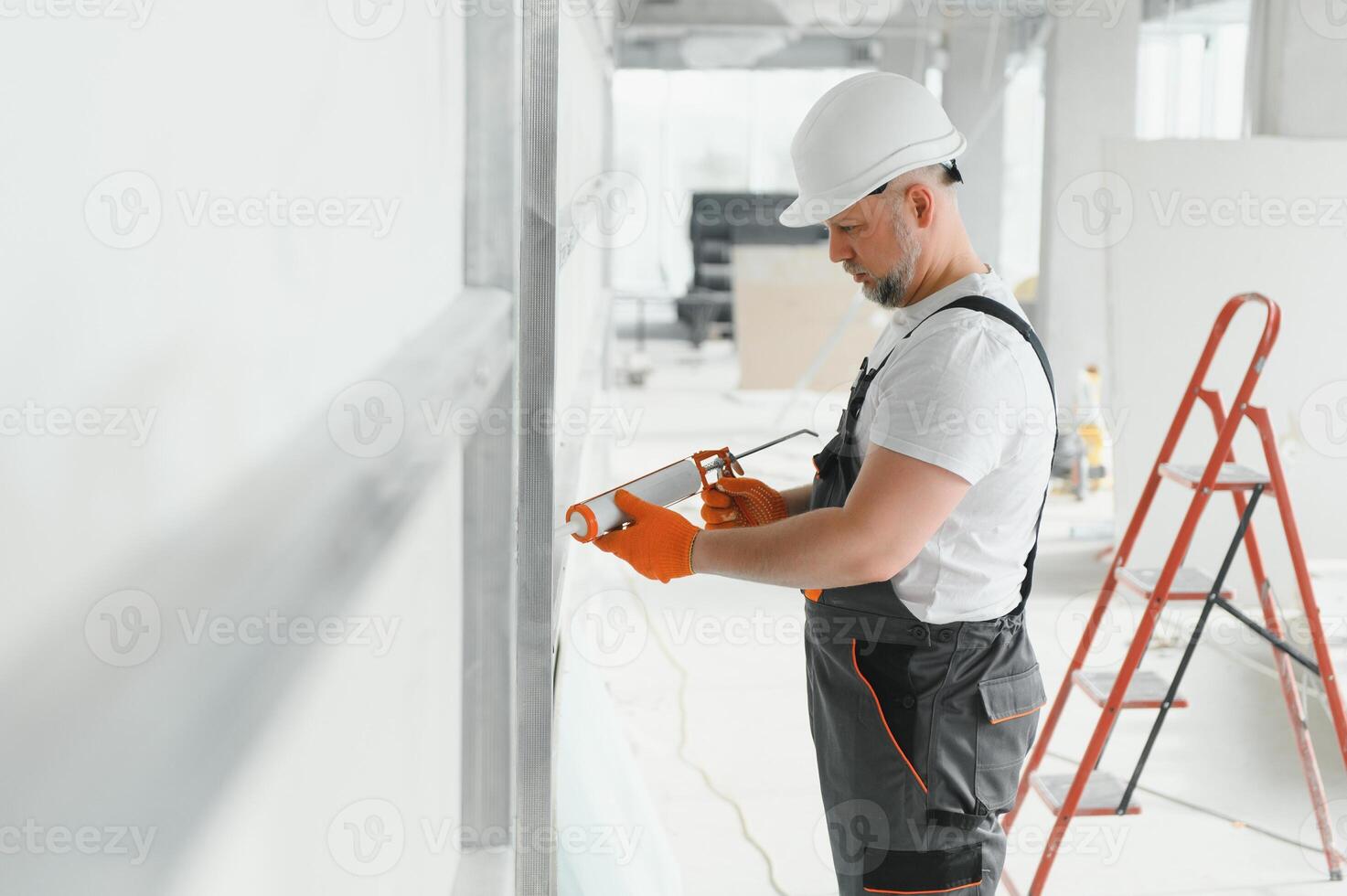 The builder fills the seam between plasterboard plates a silicone gun photo