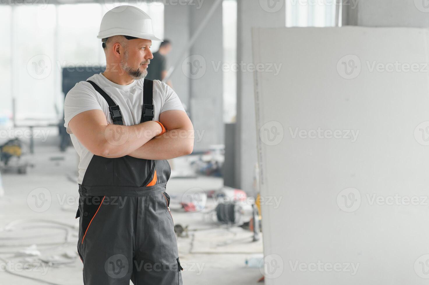 Portrait of a builder in working uniform with protective helmet standing with instruments at the construction site indoors photo