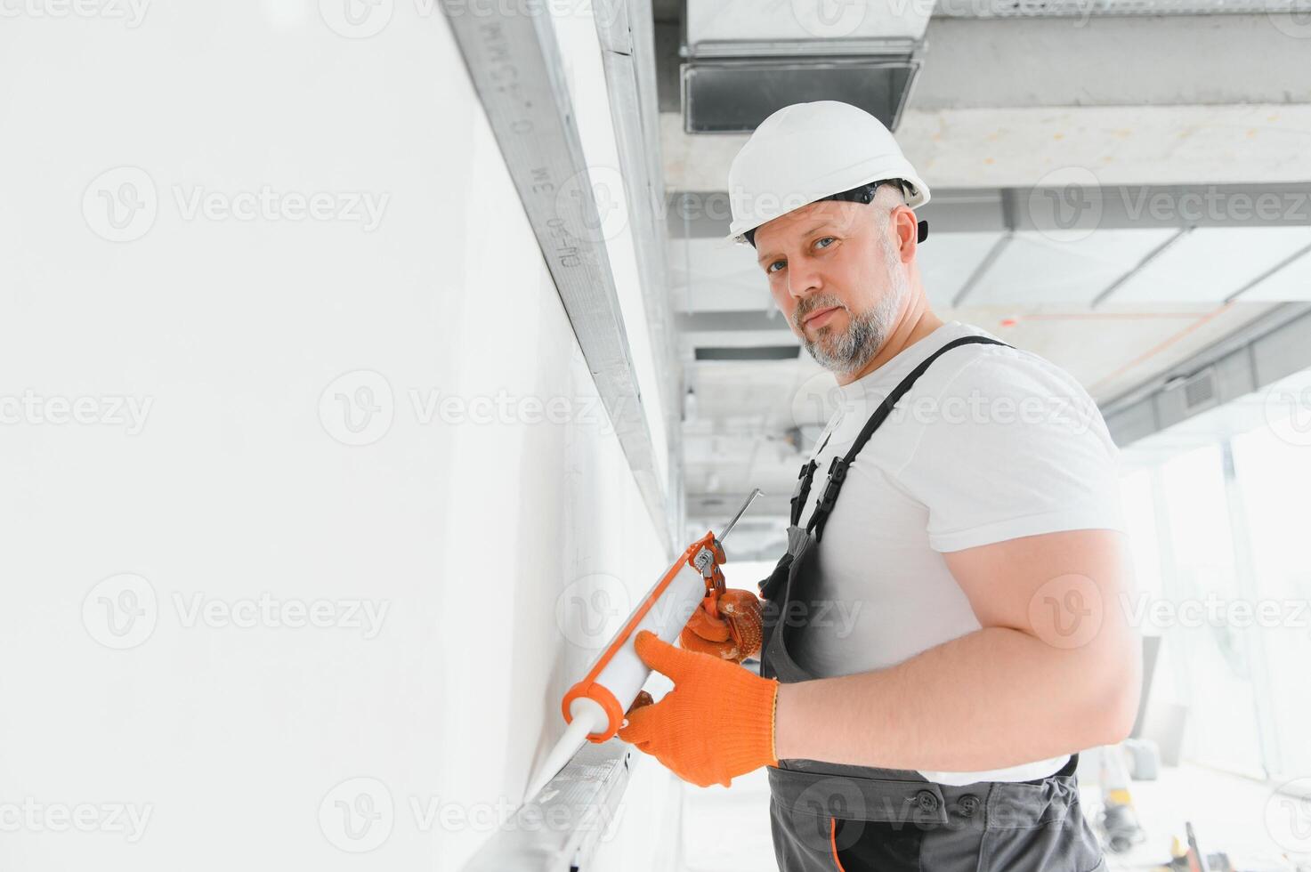 The builder fills the seam between plasterboard plates a silicone gun photo