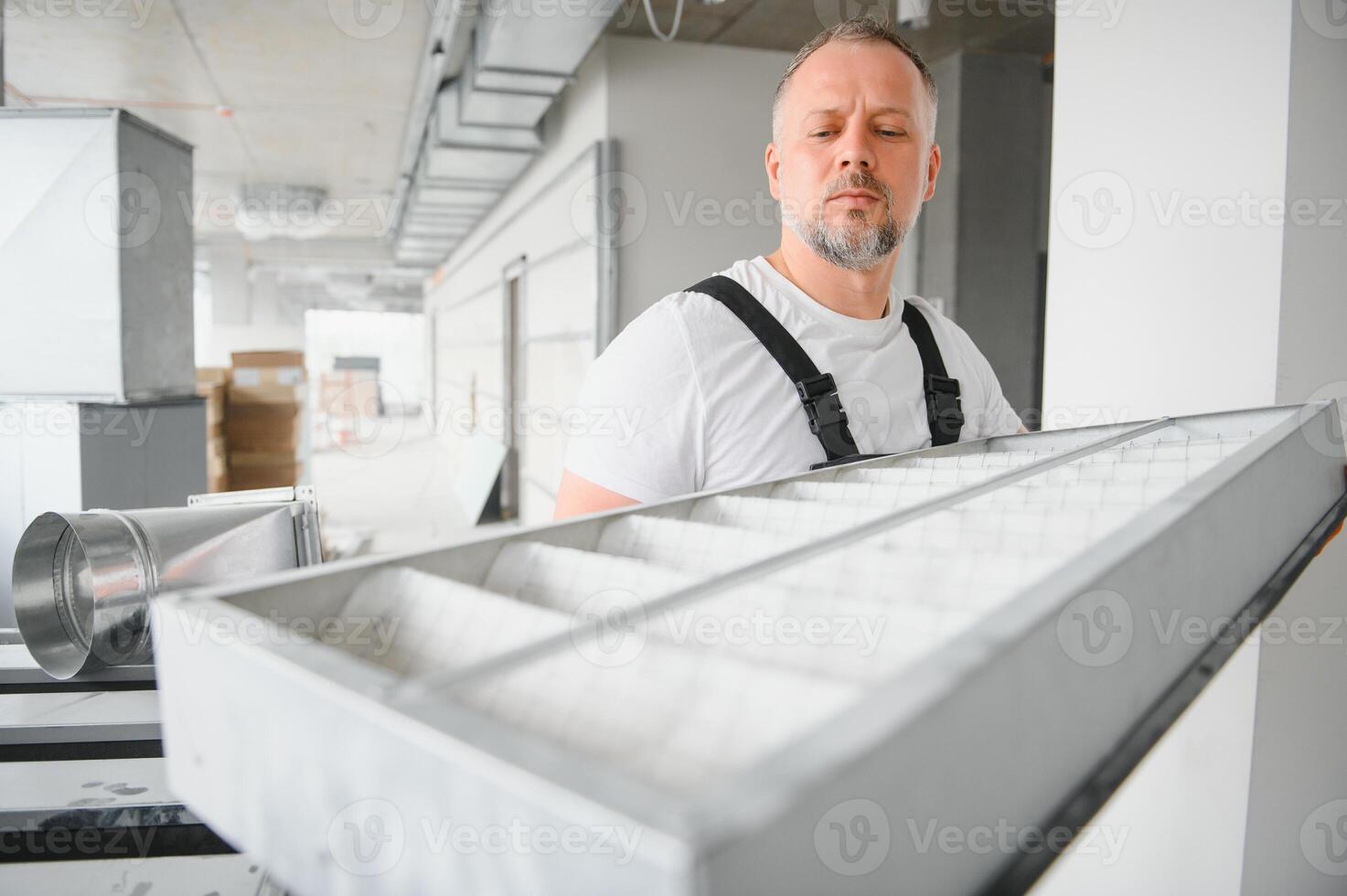 A male worker holds an air filter for air conditioning in an office space. Installation of an air conditioner. photo