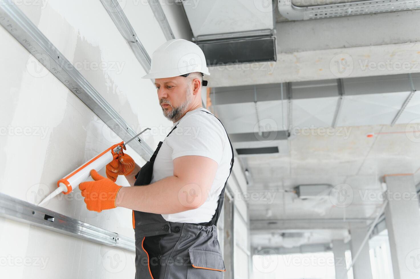 The builder fills the seam between plasterboard plates a silicone gun photo