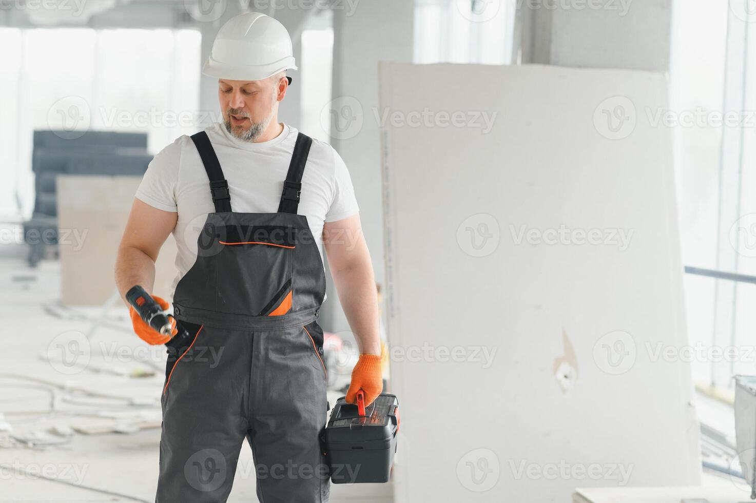 Portrait of a builder in working uniform with protective helmet standing with instruments at the construction site indoors photo
