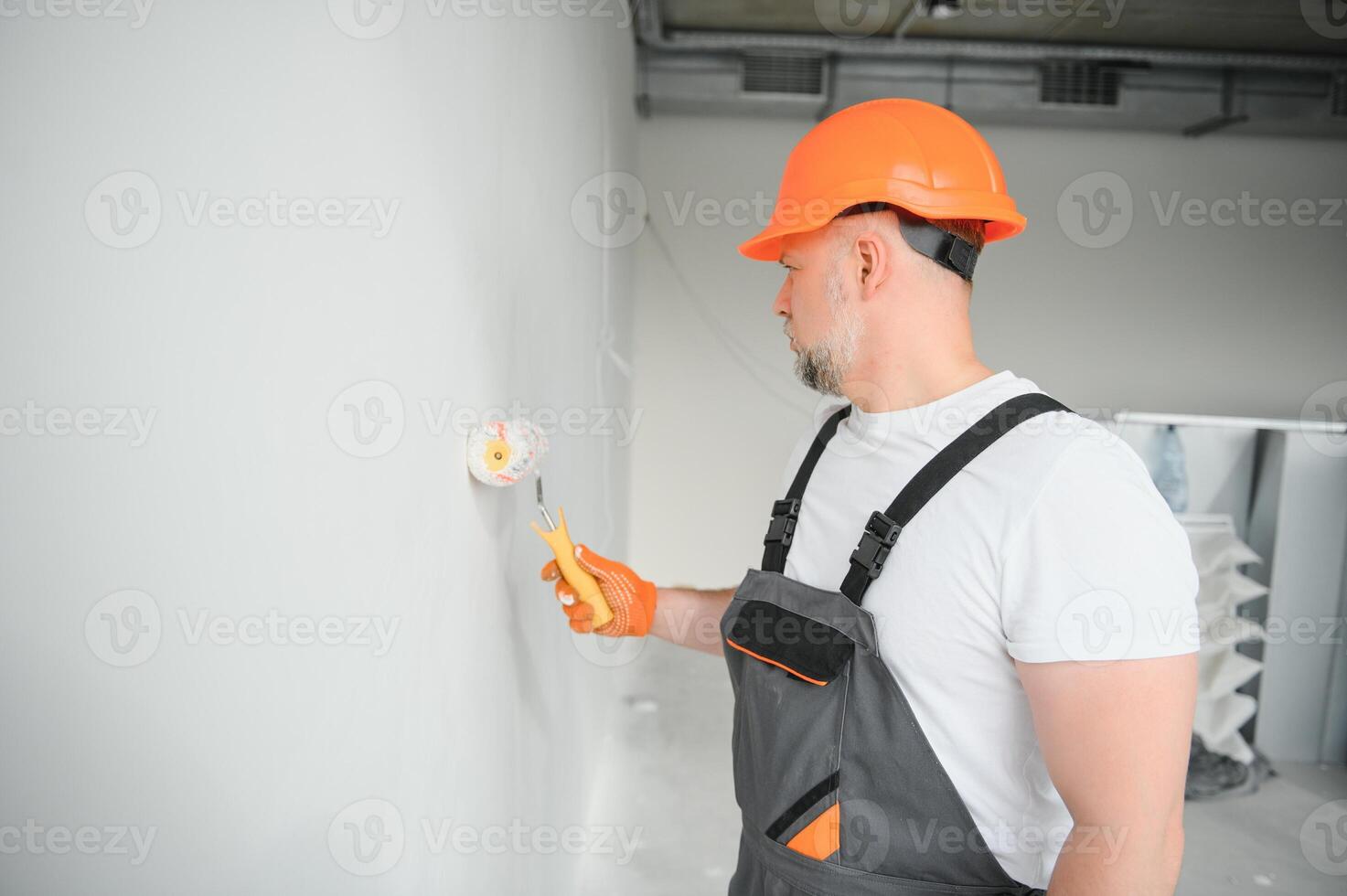Painter man painting the wall in home, with paint roller and white color paint. Room renovations at house. photo