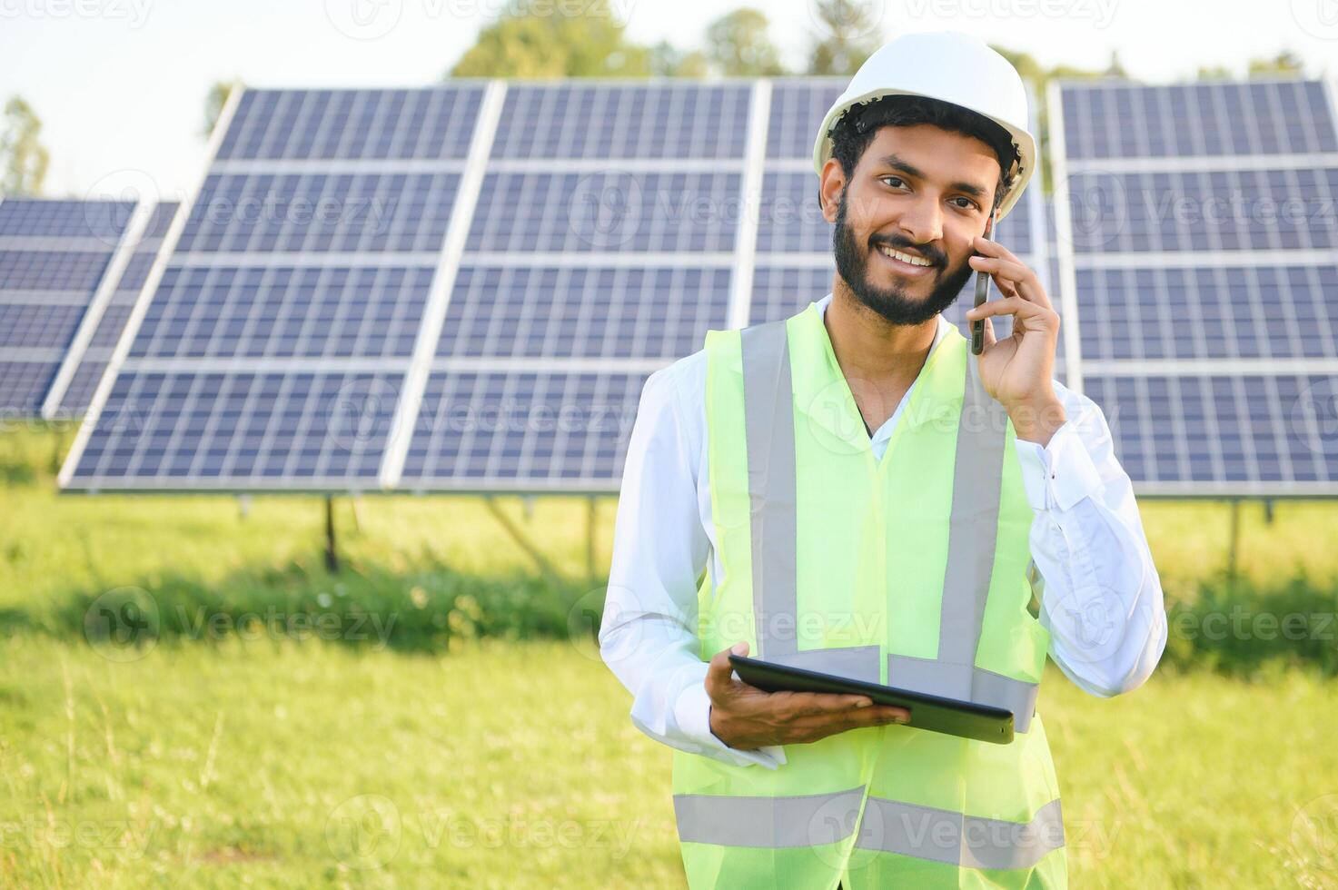male engineer checks a photovoltaic solar plant and uses a recording tablet. Indian Man in uniform holding tablet. photo