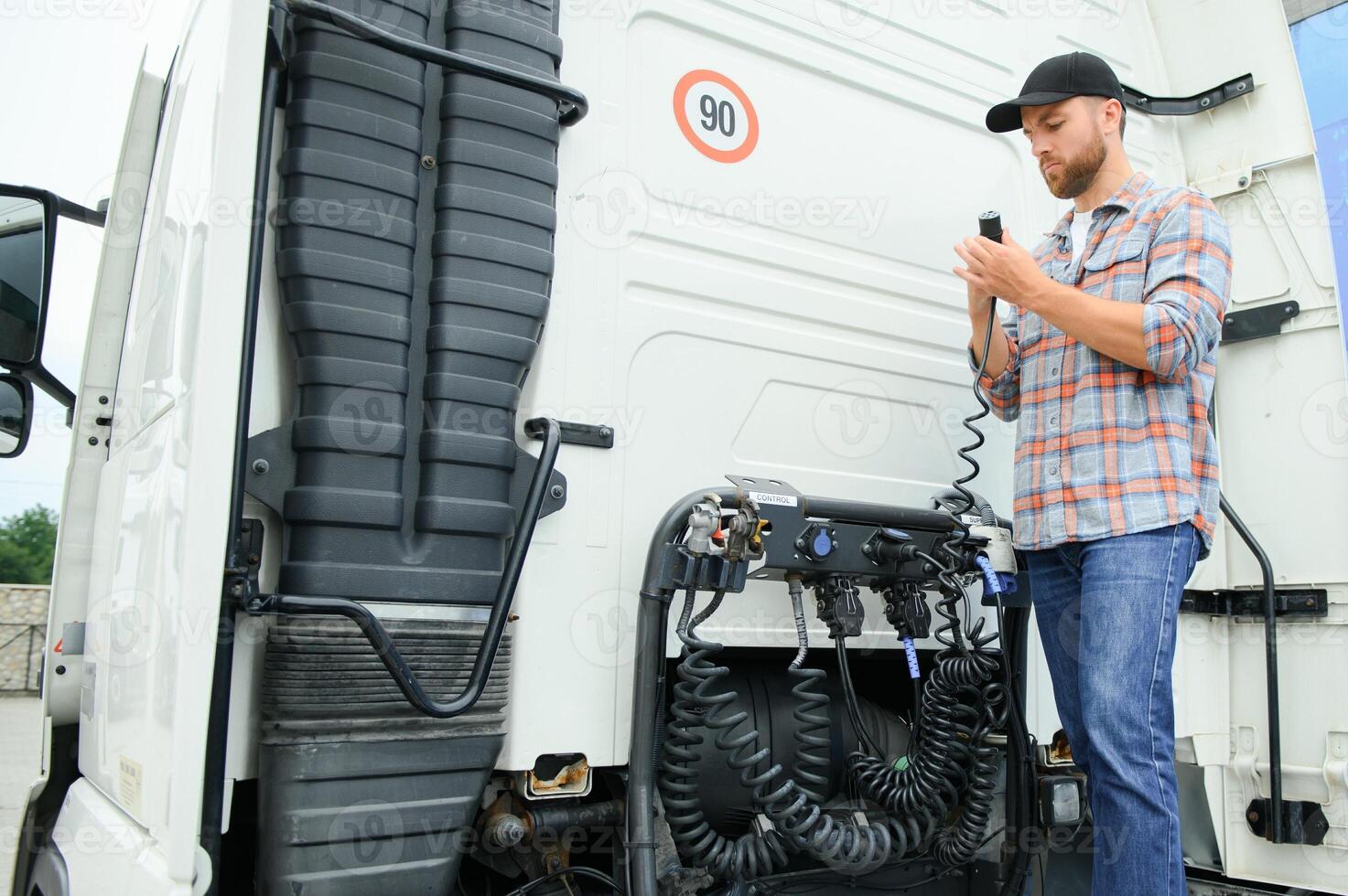 View of a driver connecting the power cables to trailer of a commercial truck. photo