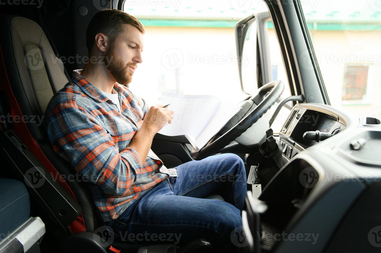 forwarder driver sits behind the wheel of a car and examines waybills documentation for the cargo. photo